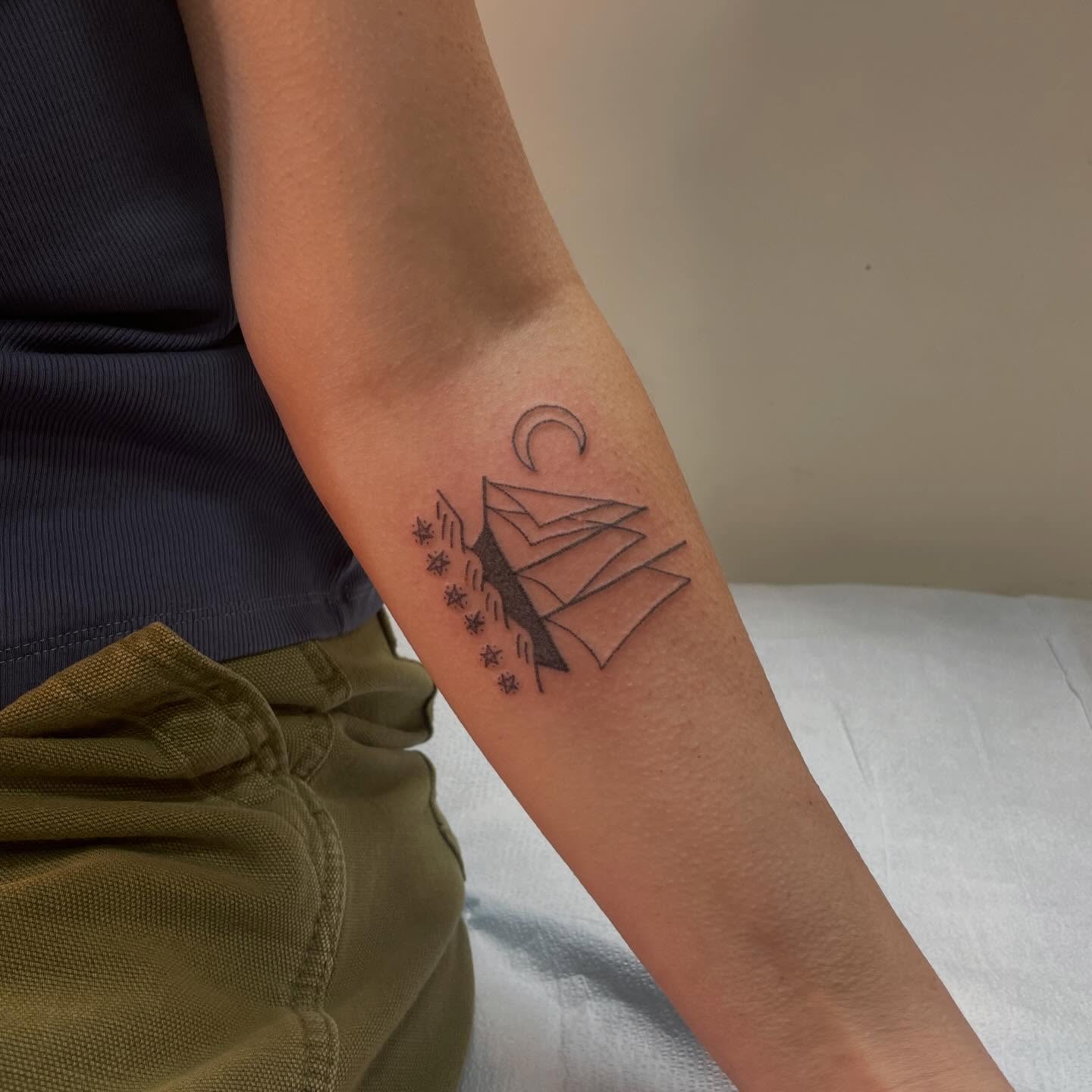 Mountain and crescent moon geometric tattoo on the forearm by Roe