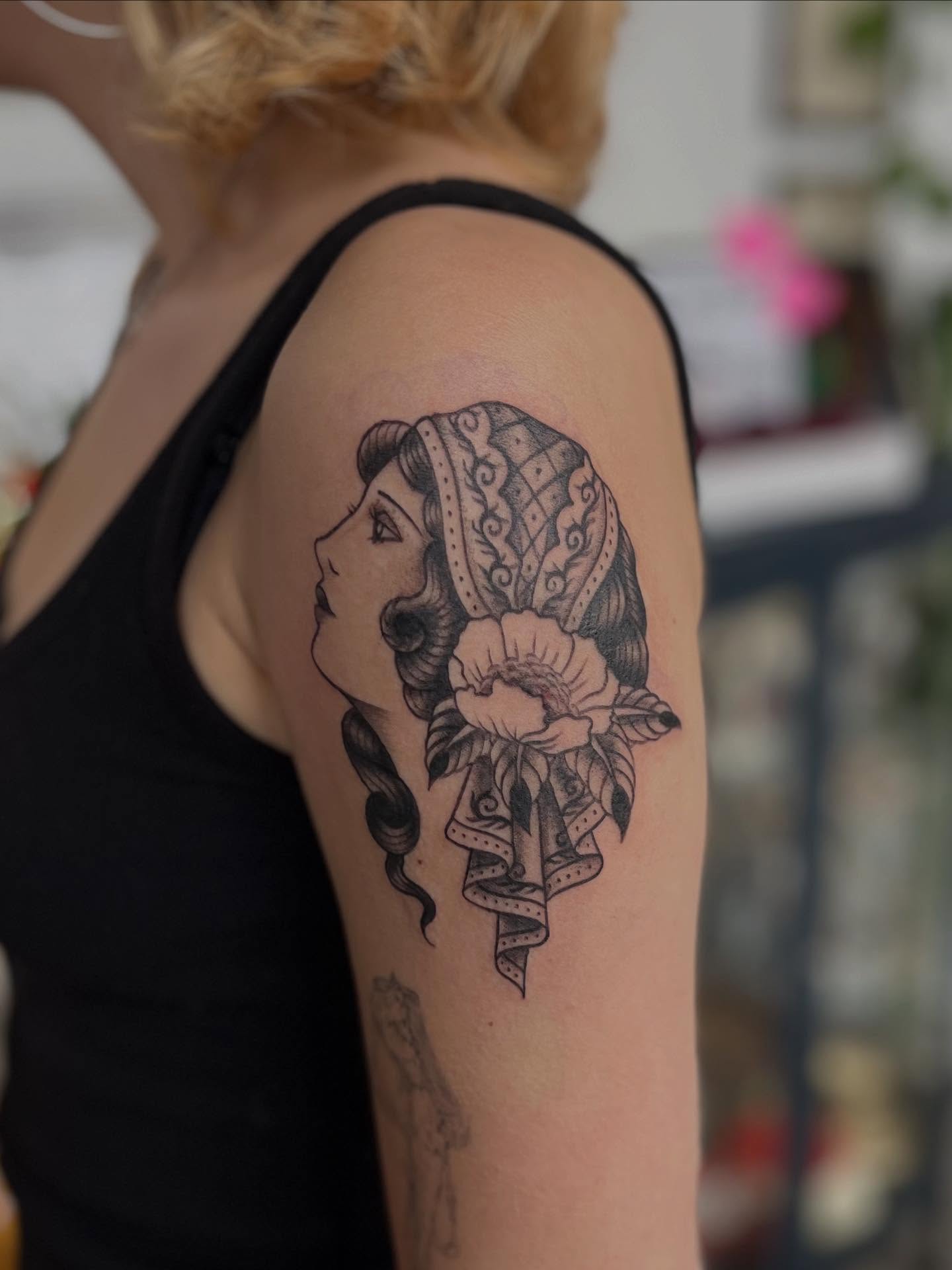 Woman with floral headpiece American traditional tattoo on the shoulder by Maddy Anthony