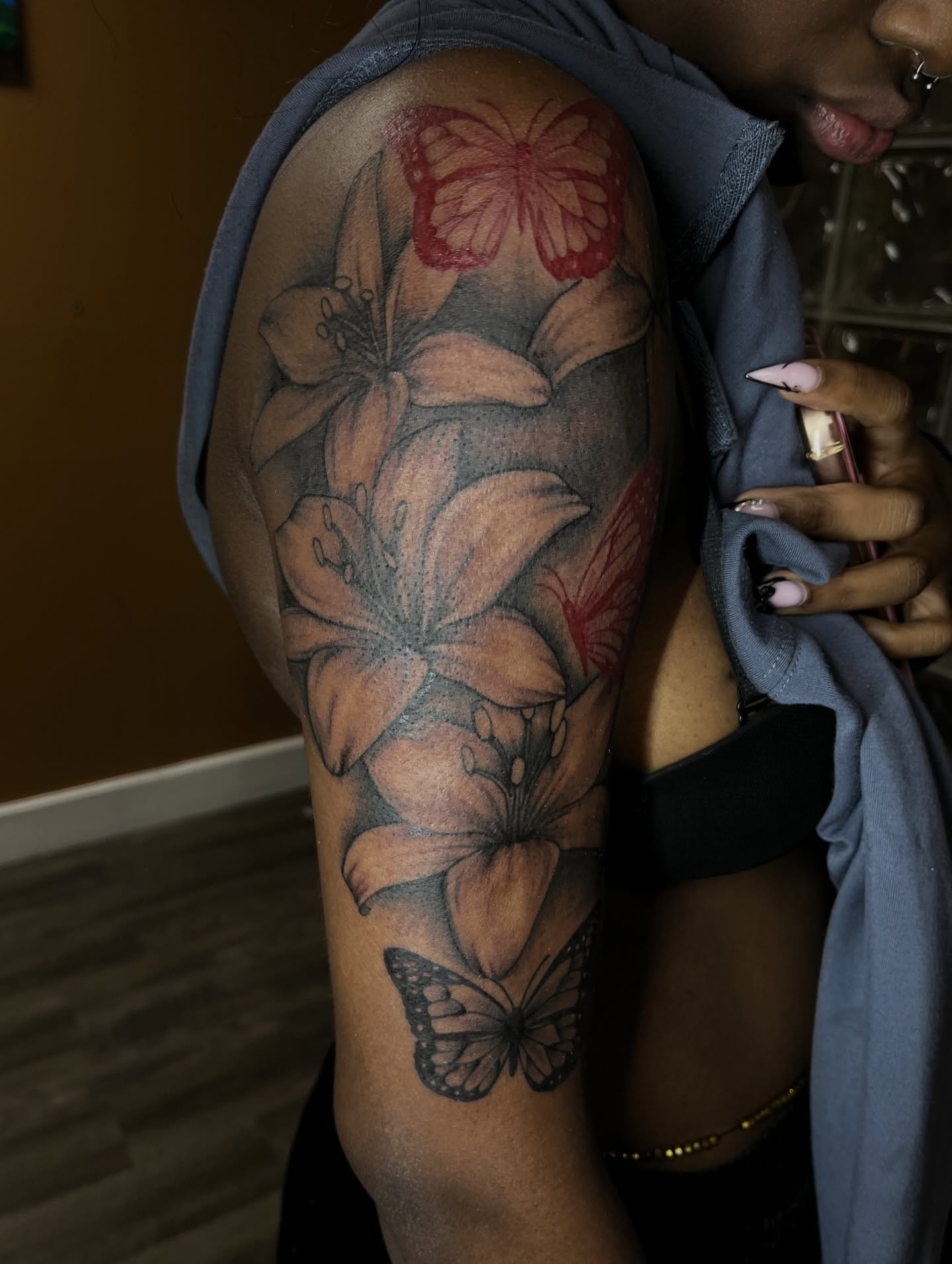Lilies and butterflies realism tattoo on the upper arm by Tam💟👩🏽‍🎨
