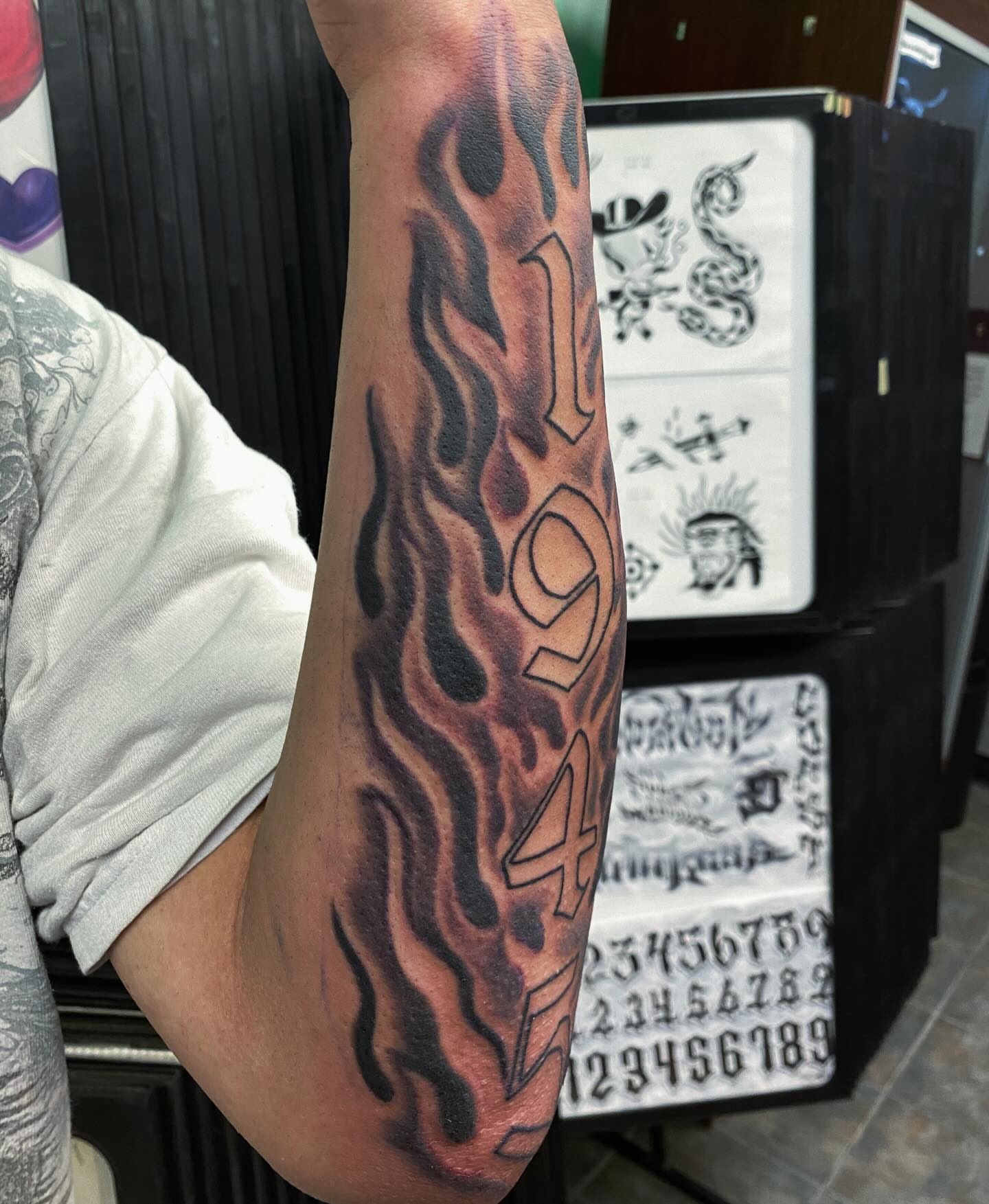 Flames and numbers black and grey tattoo on the forearm by Houston tattoo artist