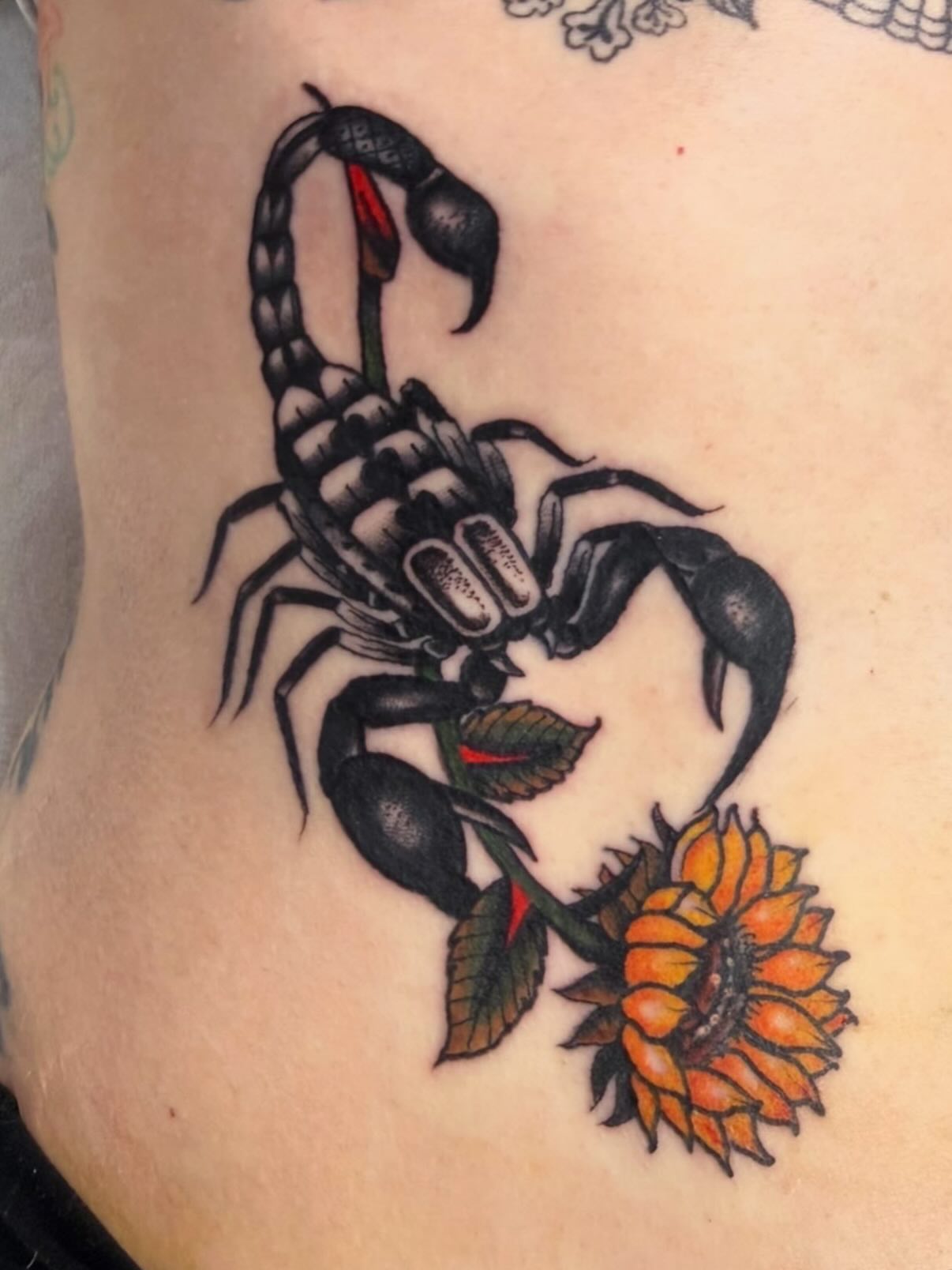 Scorpion and sunflower American traditional tattoo on the thigh by David Evans