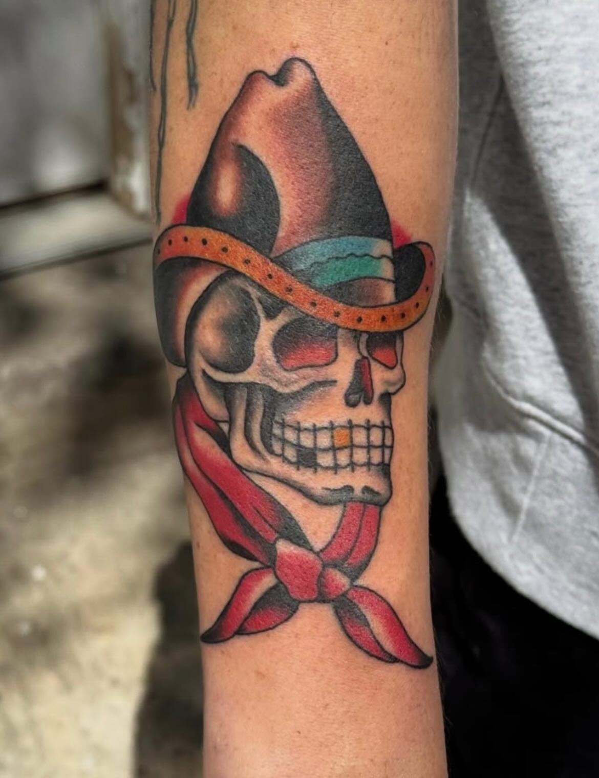 Skull wearing cowboy hat and bandana American traditional tattoo on the forearm by Jack Hatchet Tattoos