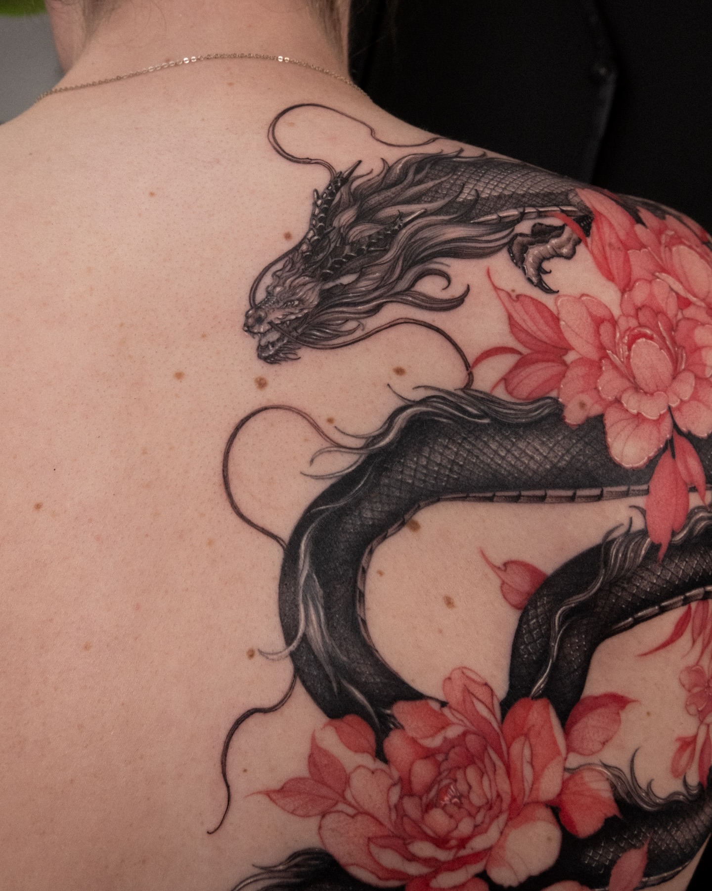 Dragon and flowers realism tattoo on the back by Wong Lee