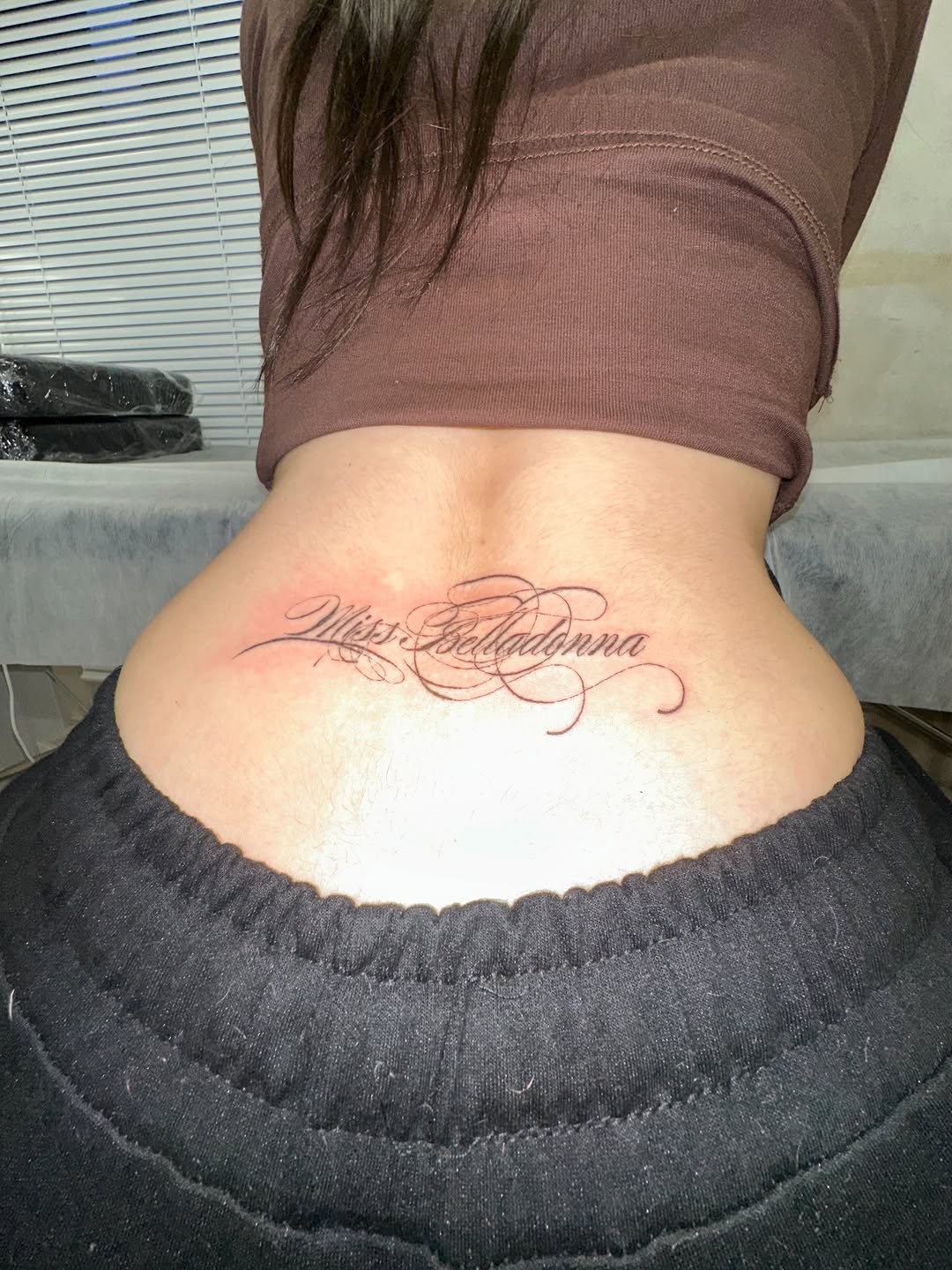 Script lettering 'Miss Belladonna' lettering tattoo on the back by eyeball
