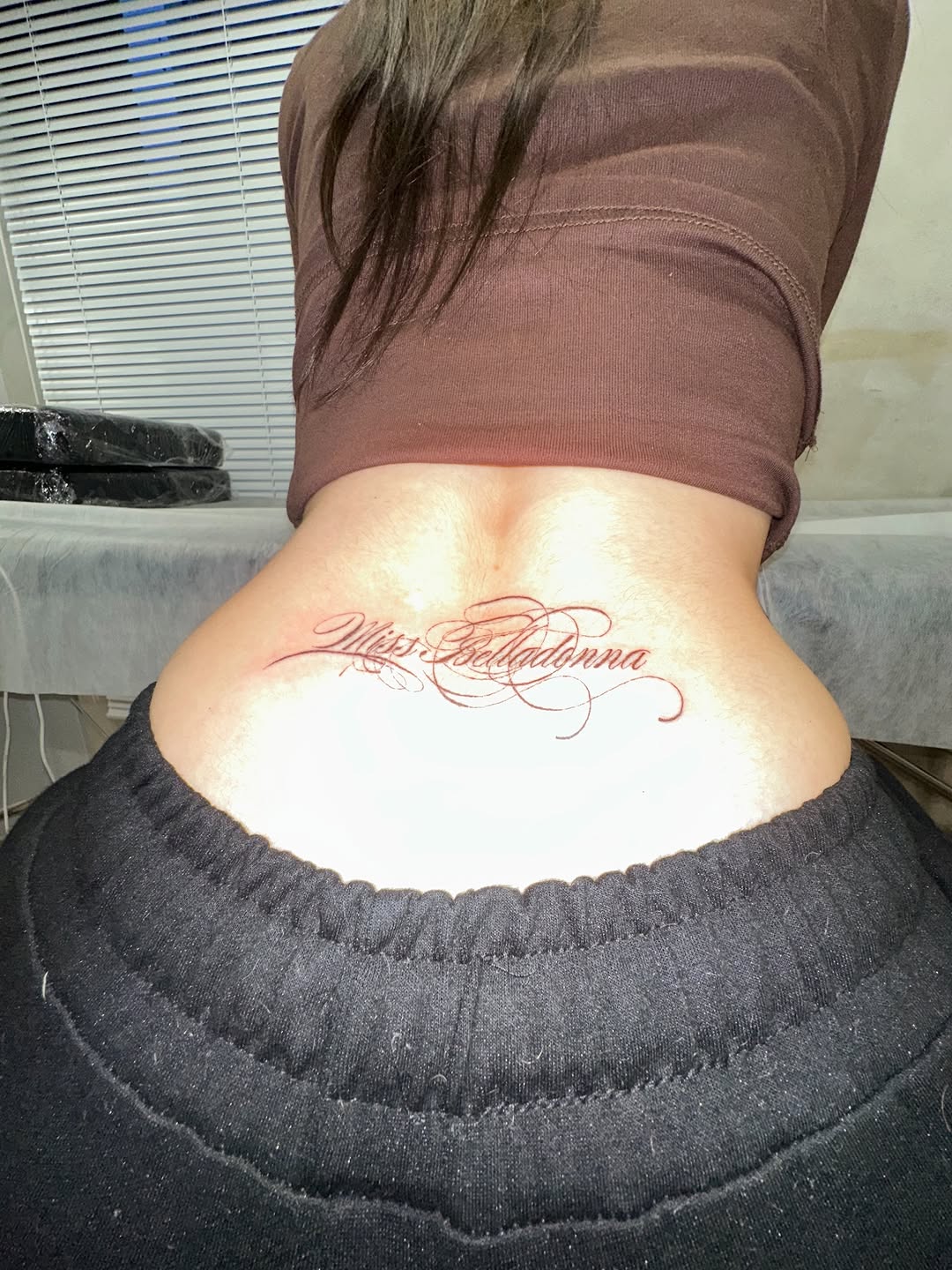 Script lettering 'Miss Belladonna' lettering tattoo on the back by eyeball