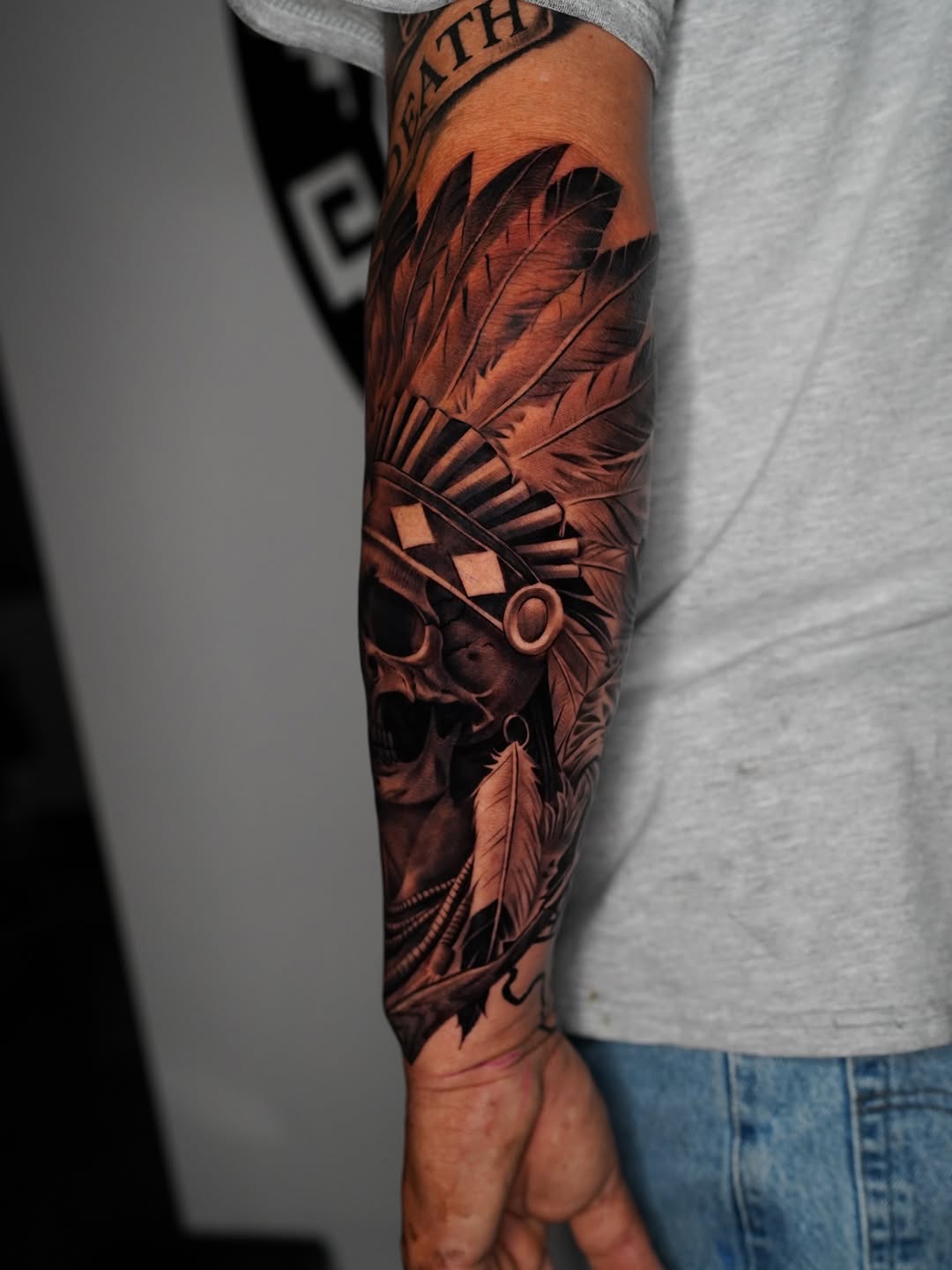 Skull with headdress and feathers realism tattoo on the forearm by Salvador Saenz Jr, Dallas, Texas