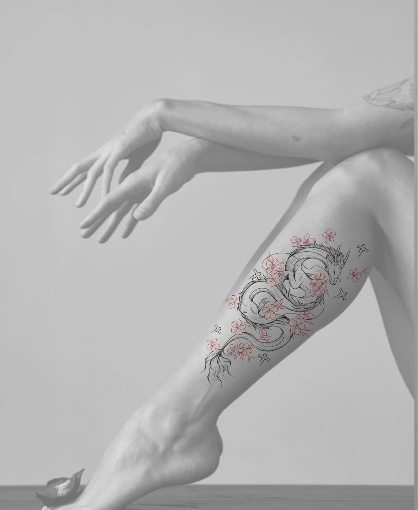 Dragon and blossoms dotwork tattoo on the thigh by Ethan
