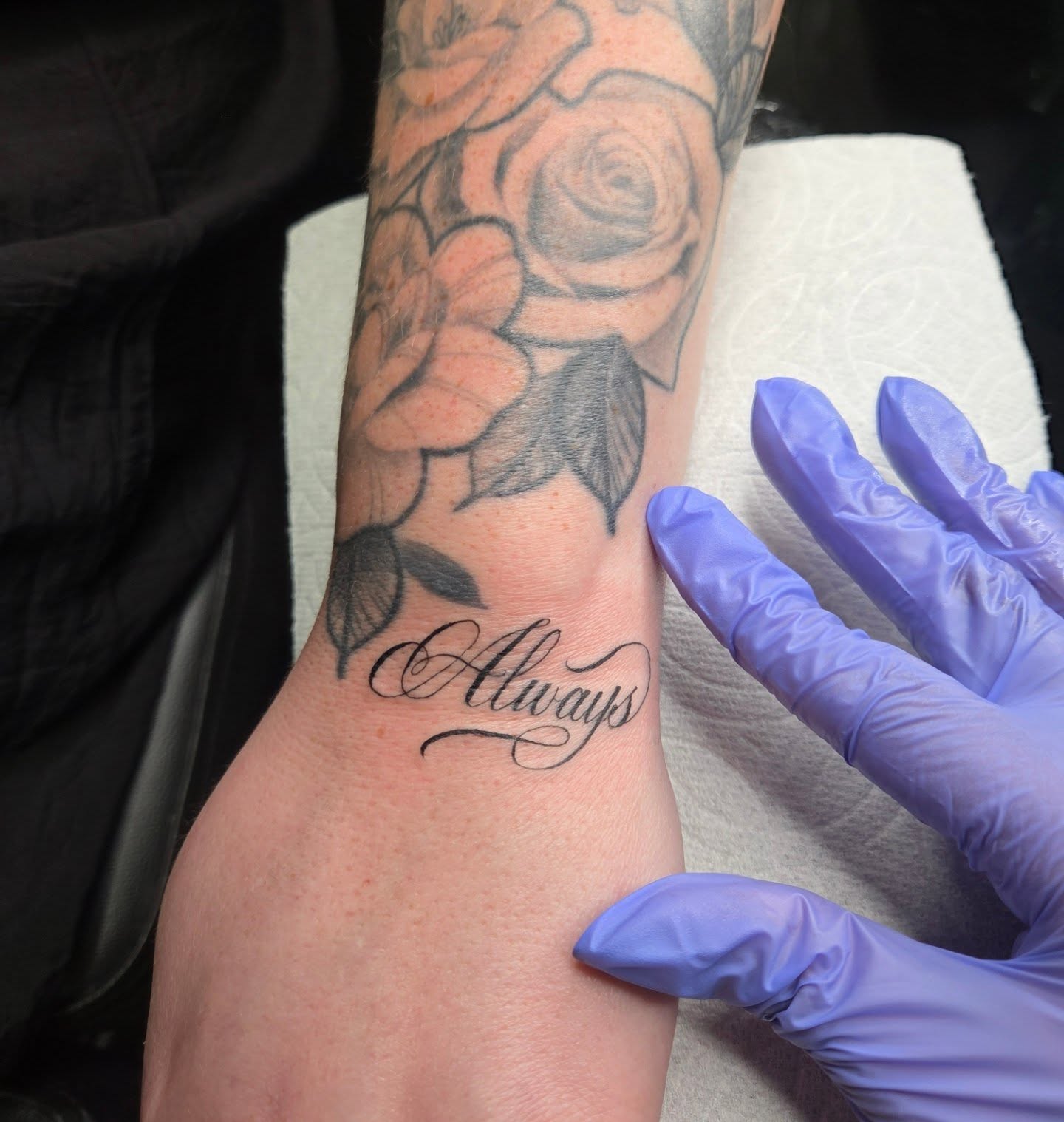 Flowers and cursive black and grey tattoo on the forearm by Yvette Cebreros