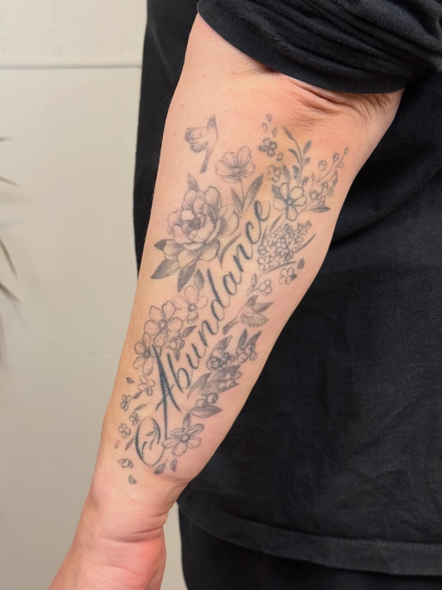Flower and bird black and grey tattoo on the forearm by Justin Turkus