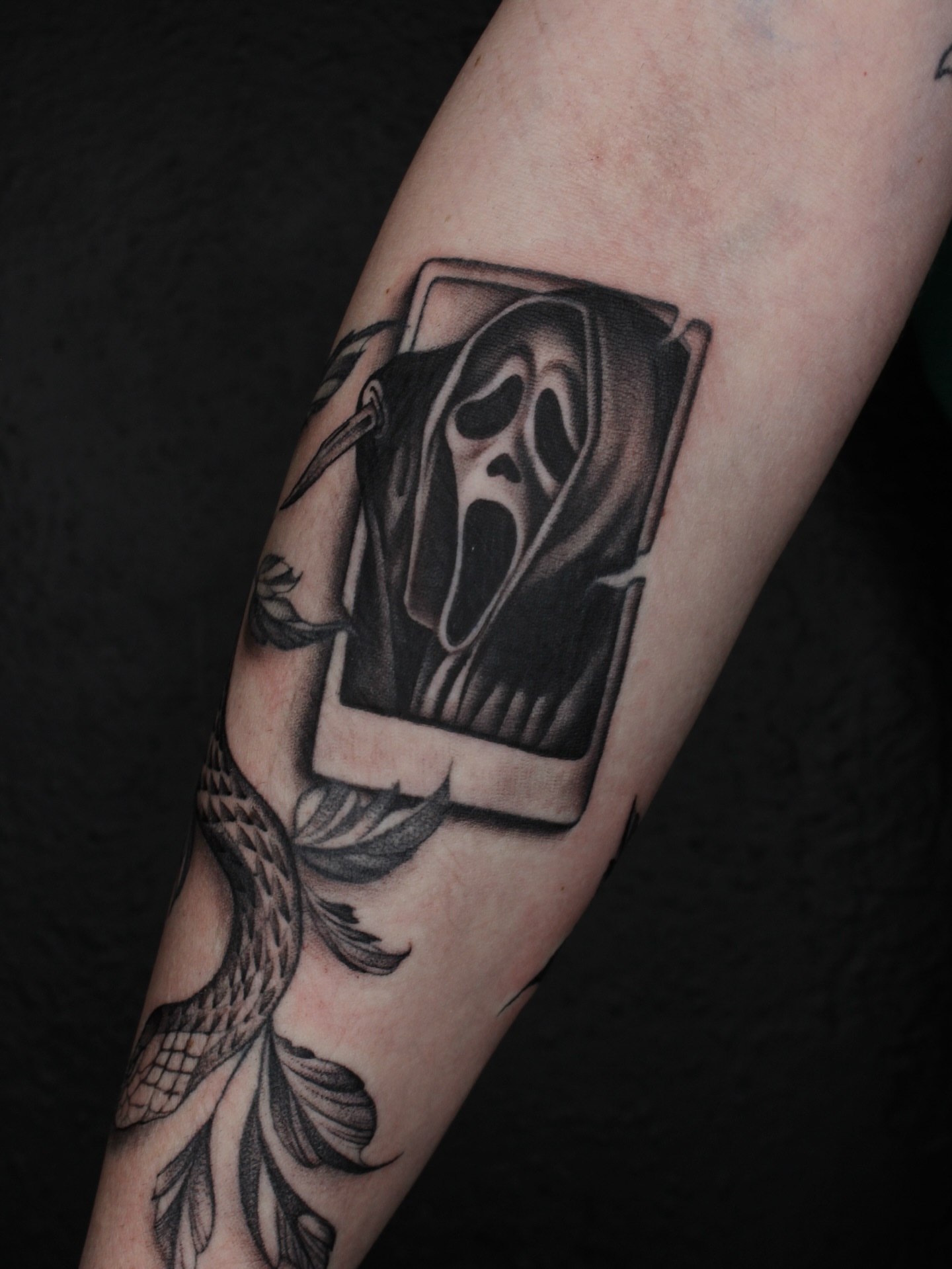Scream mask black and grey tattoo on the forearm by Jessica Roberts
