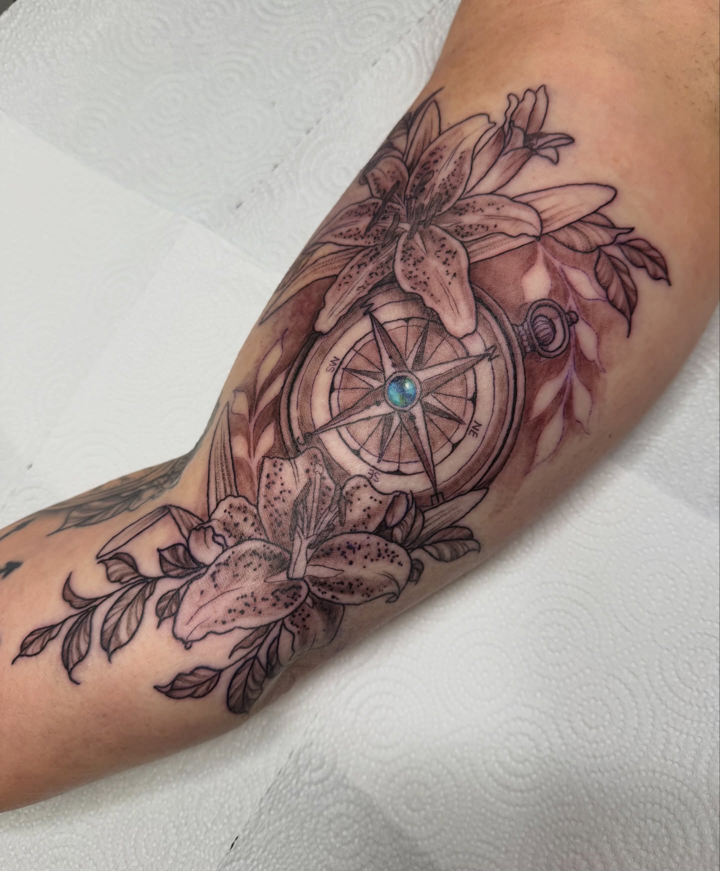 Compass and lilies realism tattoo on the forearm by Dani Fried Tattoos