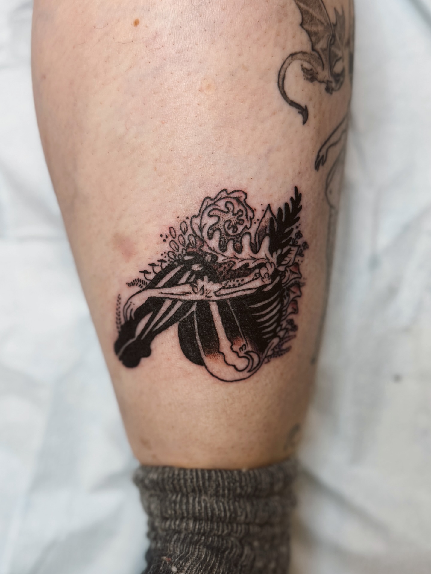 Woman with roses black and grey tattoo on the calf by Emma Berger