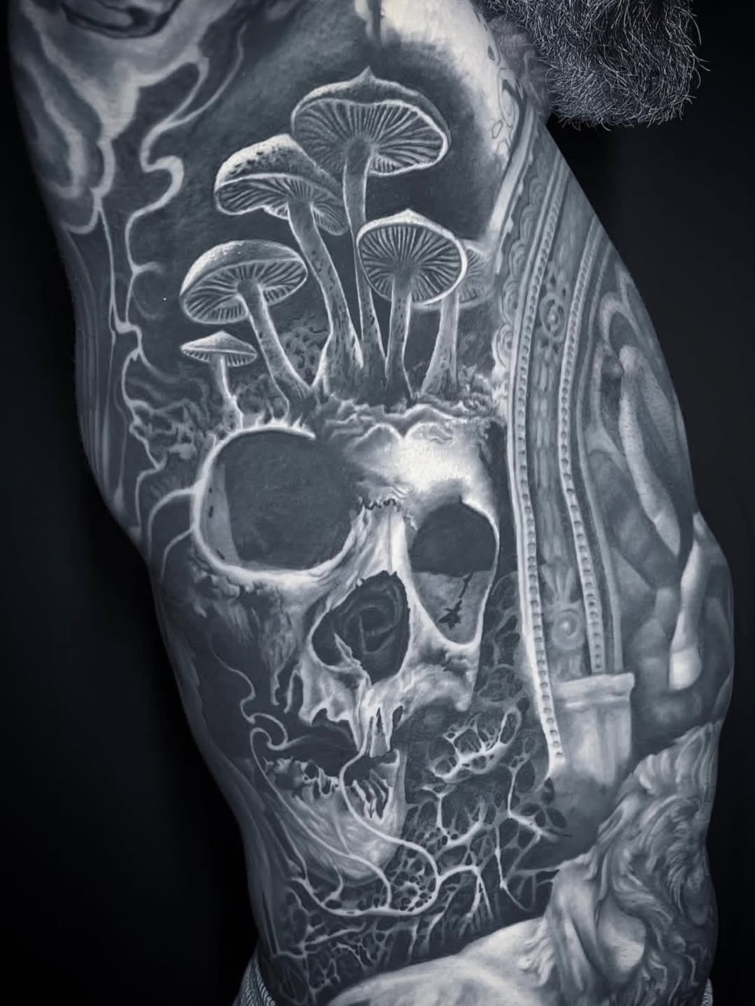 Skull with mushrooms surrealism tattoo on the forearm by Gabriel Londis