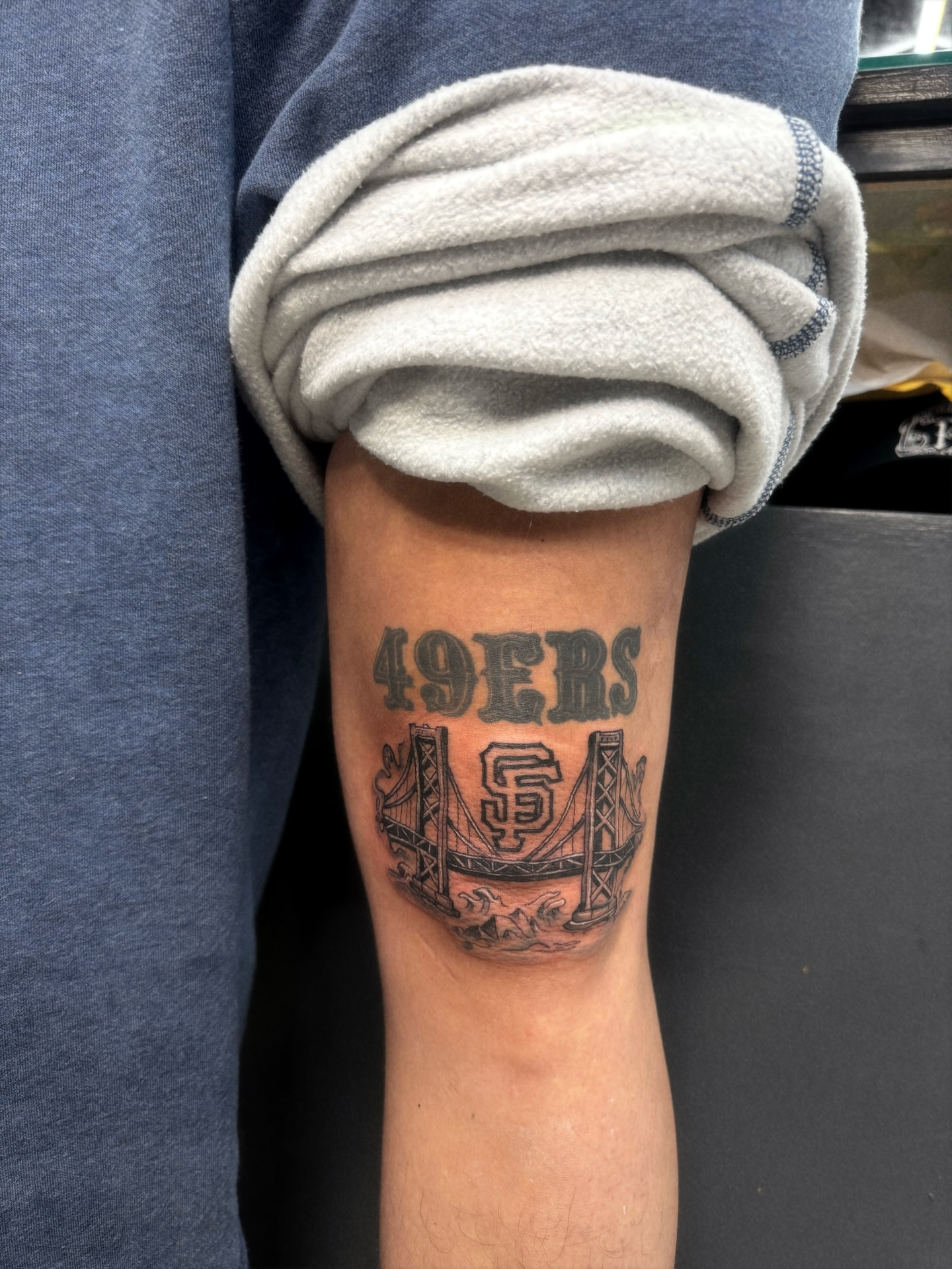 49ers logo and bridge black and grey tattoo on the forearm by 🕸️EC🥷🏼🌁🇲🇽🕸️