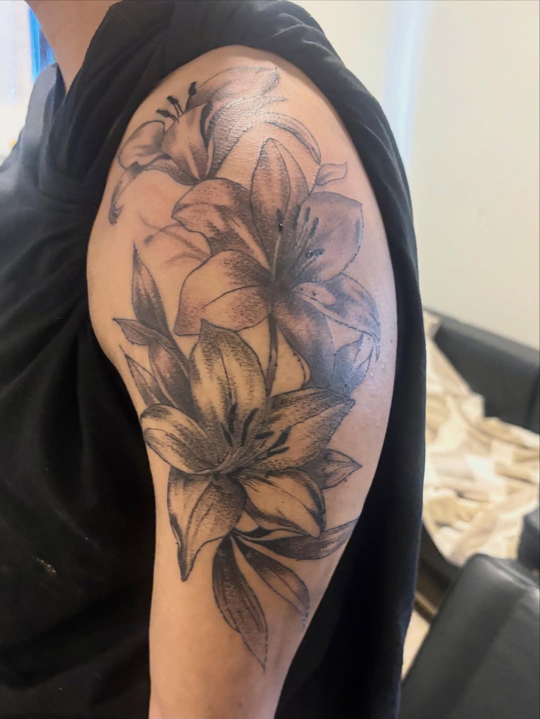 Lilies fine line tattoo on the shoulder by sams tattoos