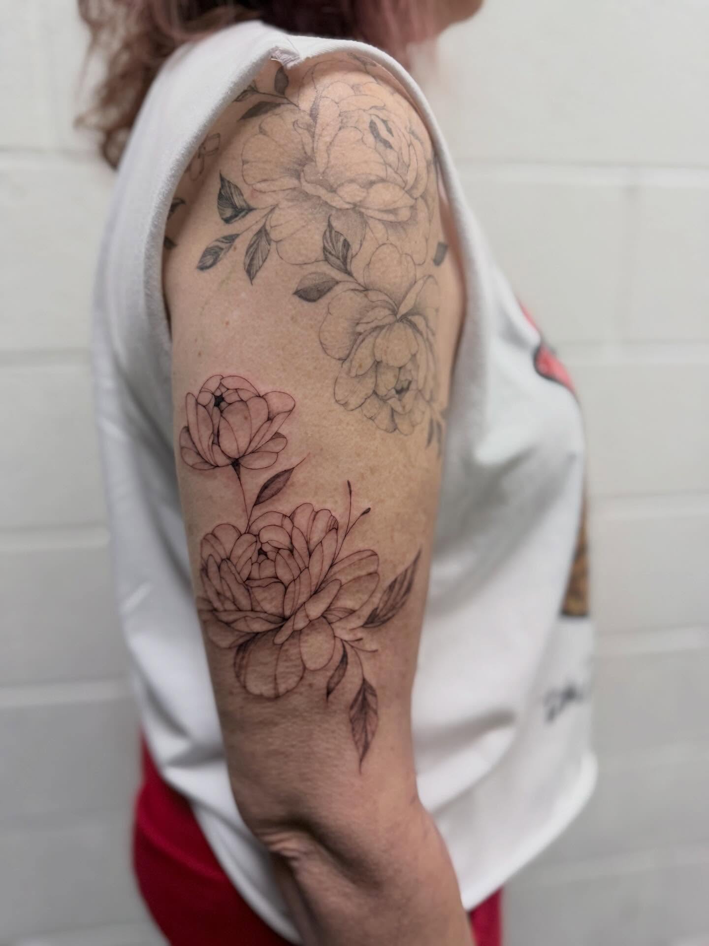 Peony flowers black and grey tattoo on the upper arm by Reverie Studio
