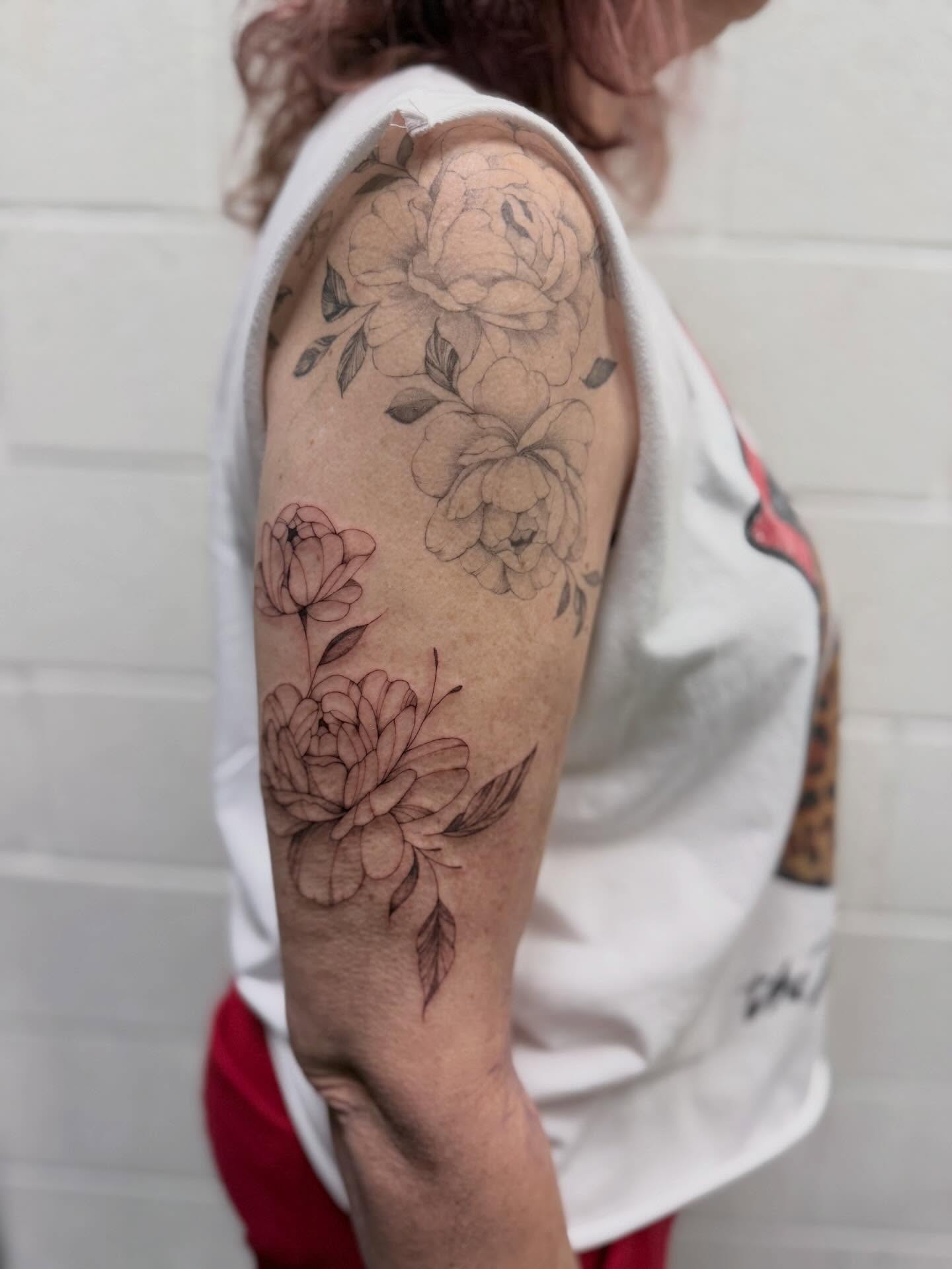 Floral arrangement black and grey tattoo on the upper arm by Reverie Studio