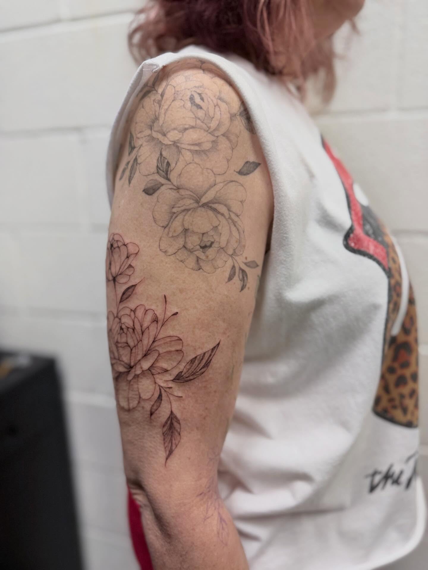 Floral bouquet black and grey tattoo on the upper arm by Reverie Studio