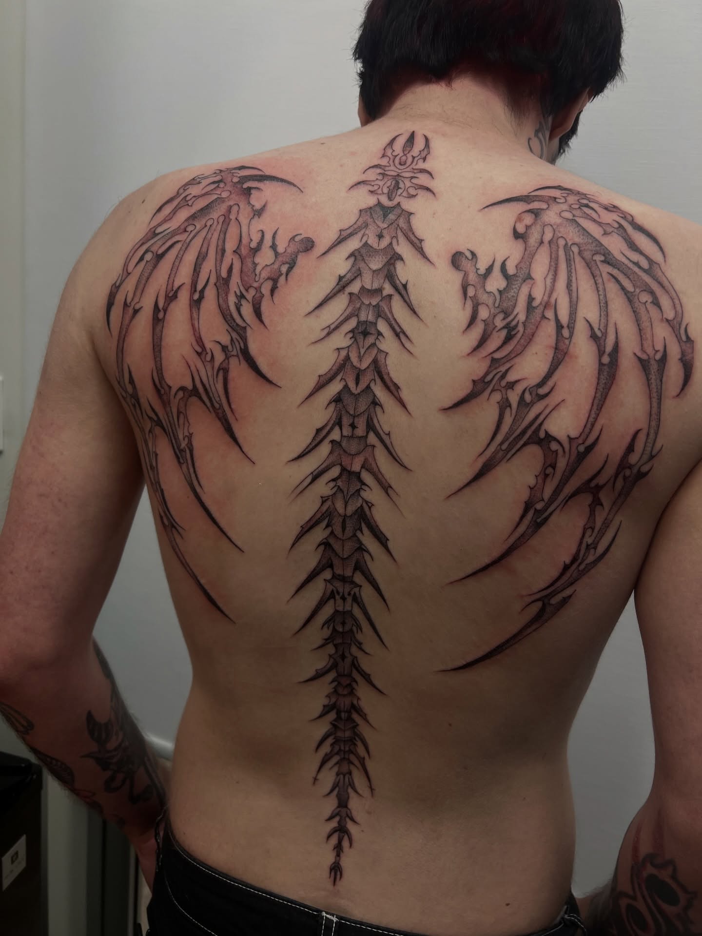 Wings and spine black and grey tattoo on the back by ashlyn rene