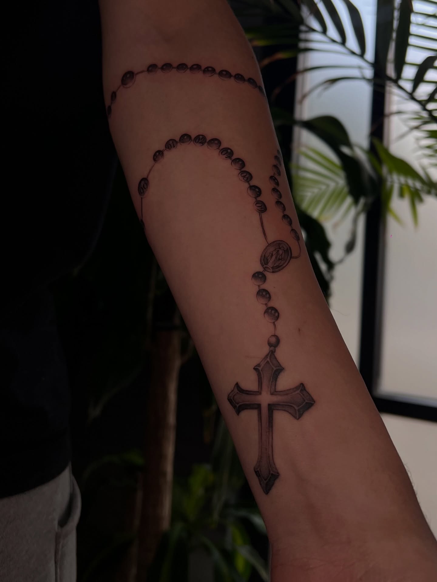 Rosary and cross black and grey tattoo on the forearm by Espi