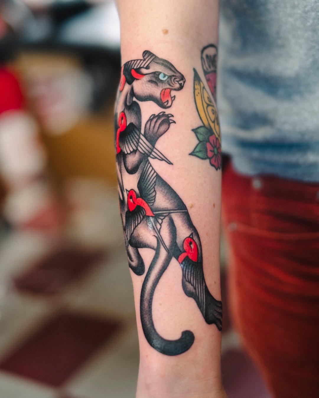 Panther with red accents American traditional tattoo on the forearm by Dan Gilsdorf, Portland, Oregon