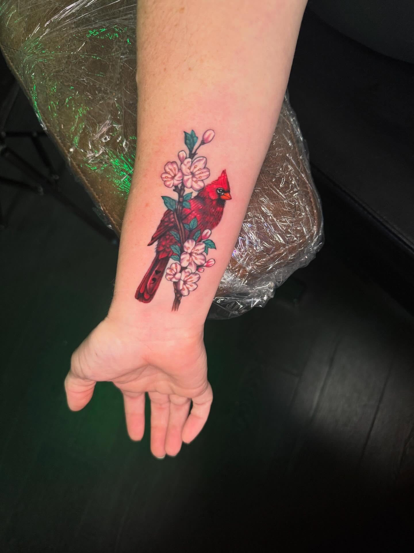 Cardinal and cherry blossoms realism tattoo on the forearm by Paige Marie Marion