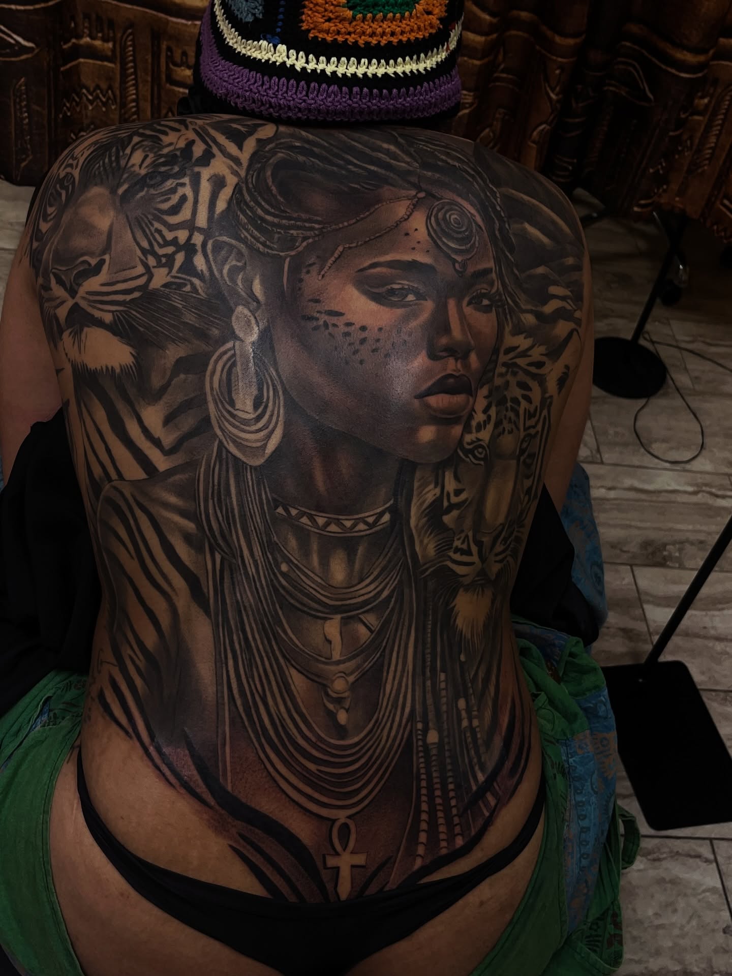 Woman with African-inspired attire realism tattoo on the back by Quinten Harper