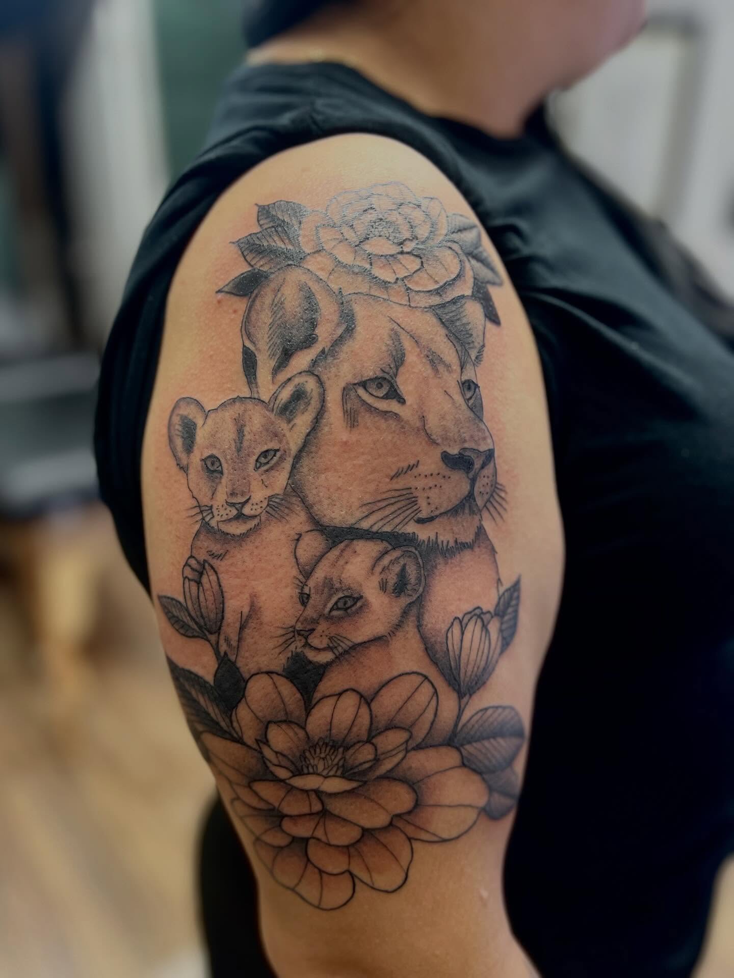 Lion family with flowers realism tattoo on the shoulder by Victorian Coleman