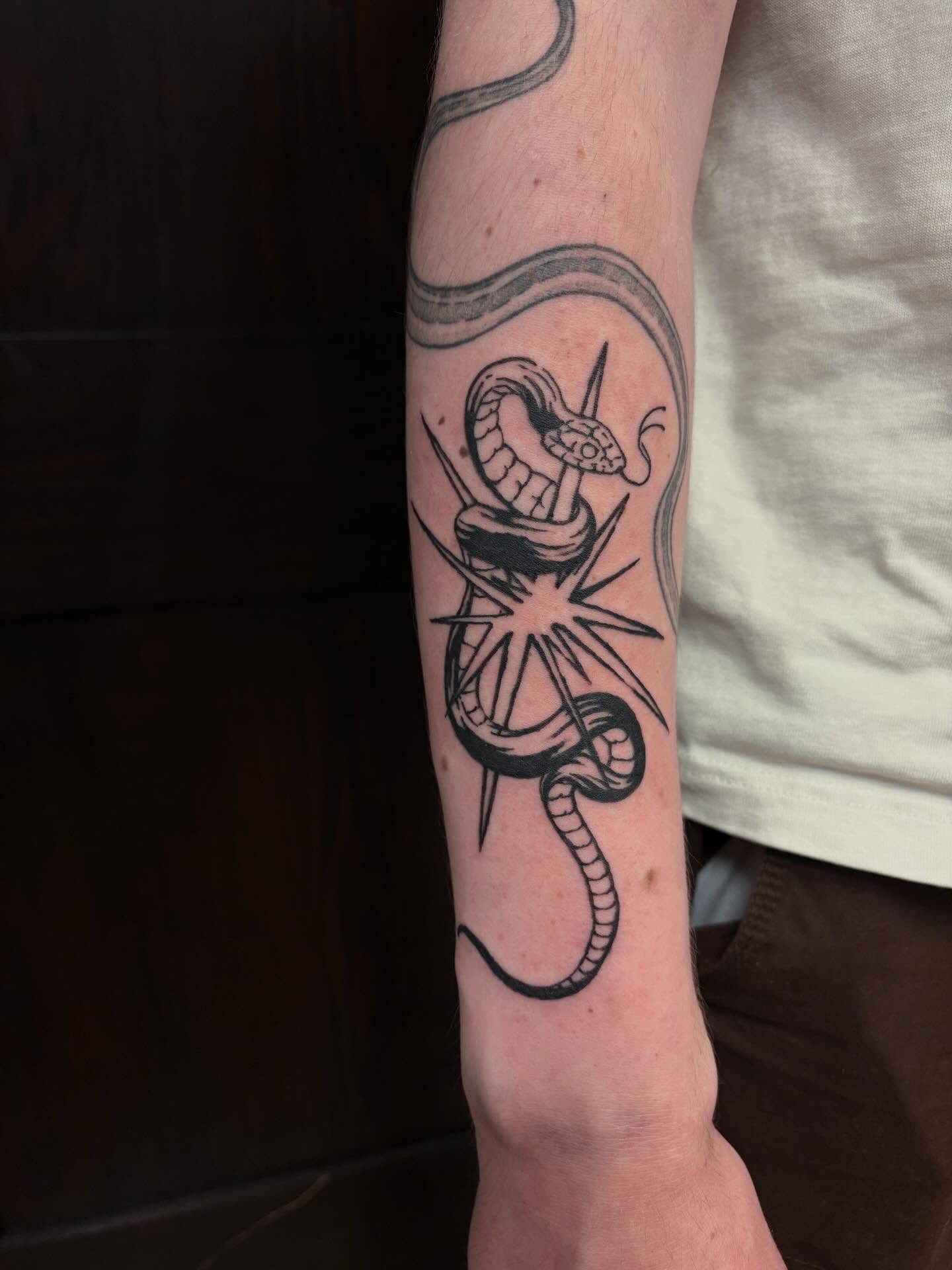 Snake and compass black and grey tattoo on the forearm by kane