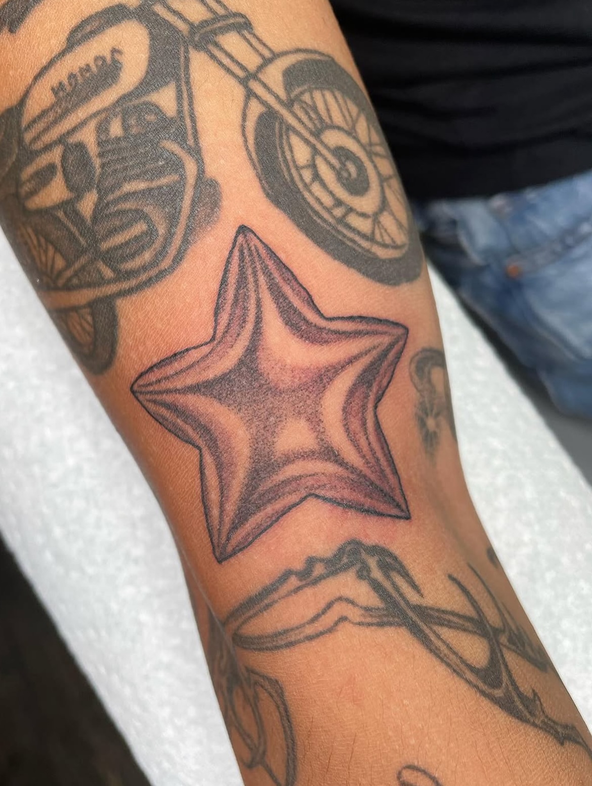 Star black and grey tattoo on the forearm by Sylvie