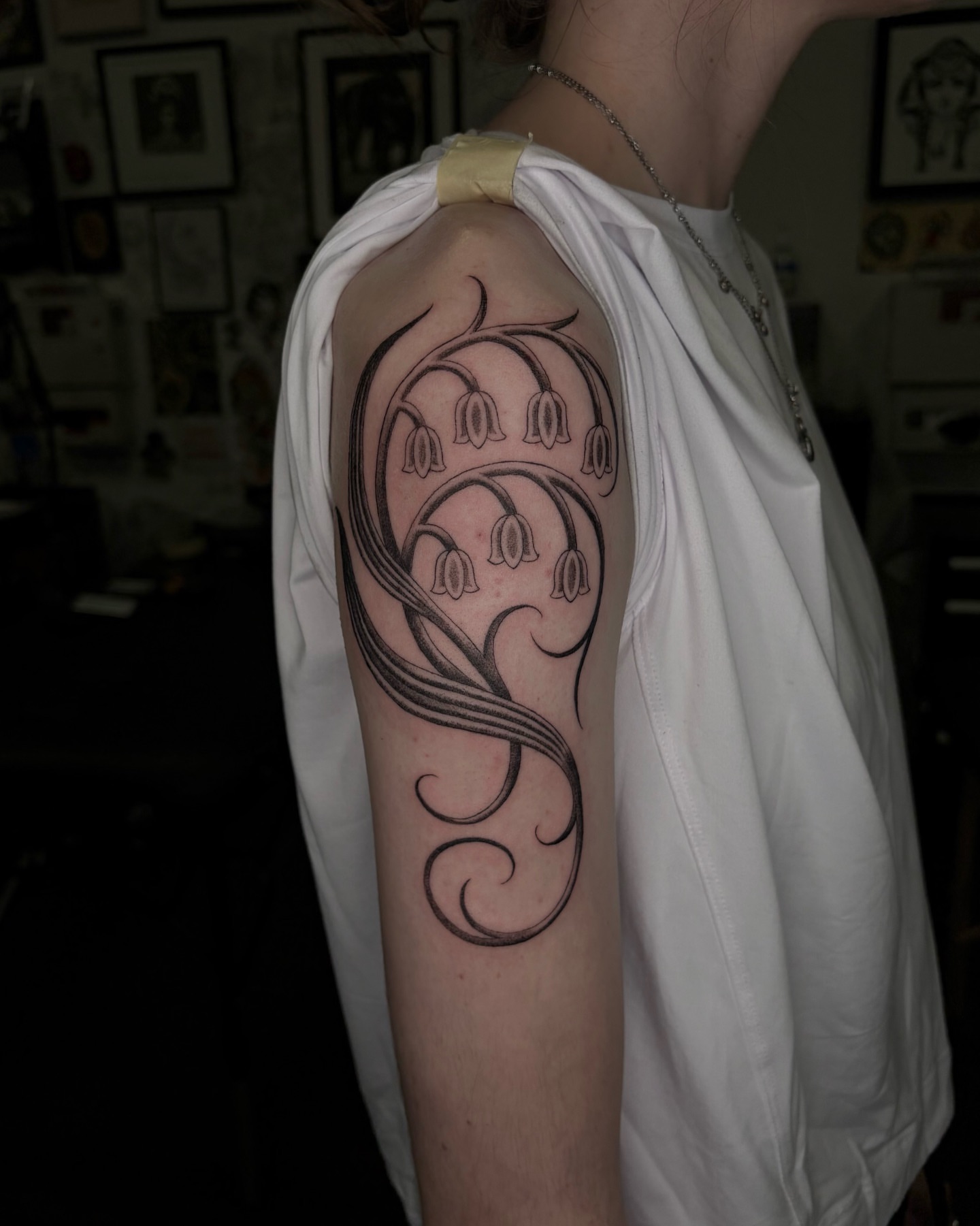 Bell-shaped flowers black and grey tattoo on the upper arm by Tattoo Artist, in San Francisco, CA
