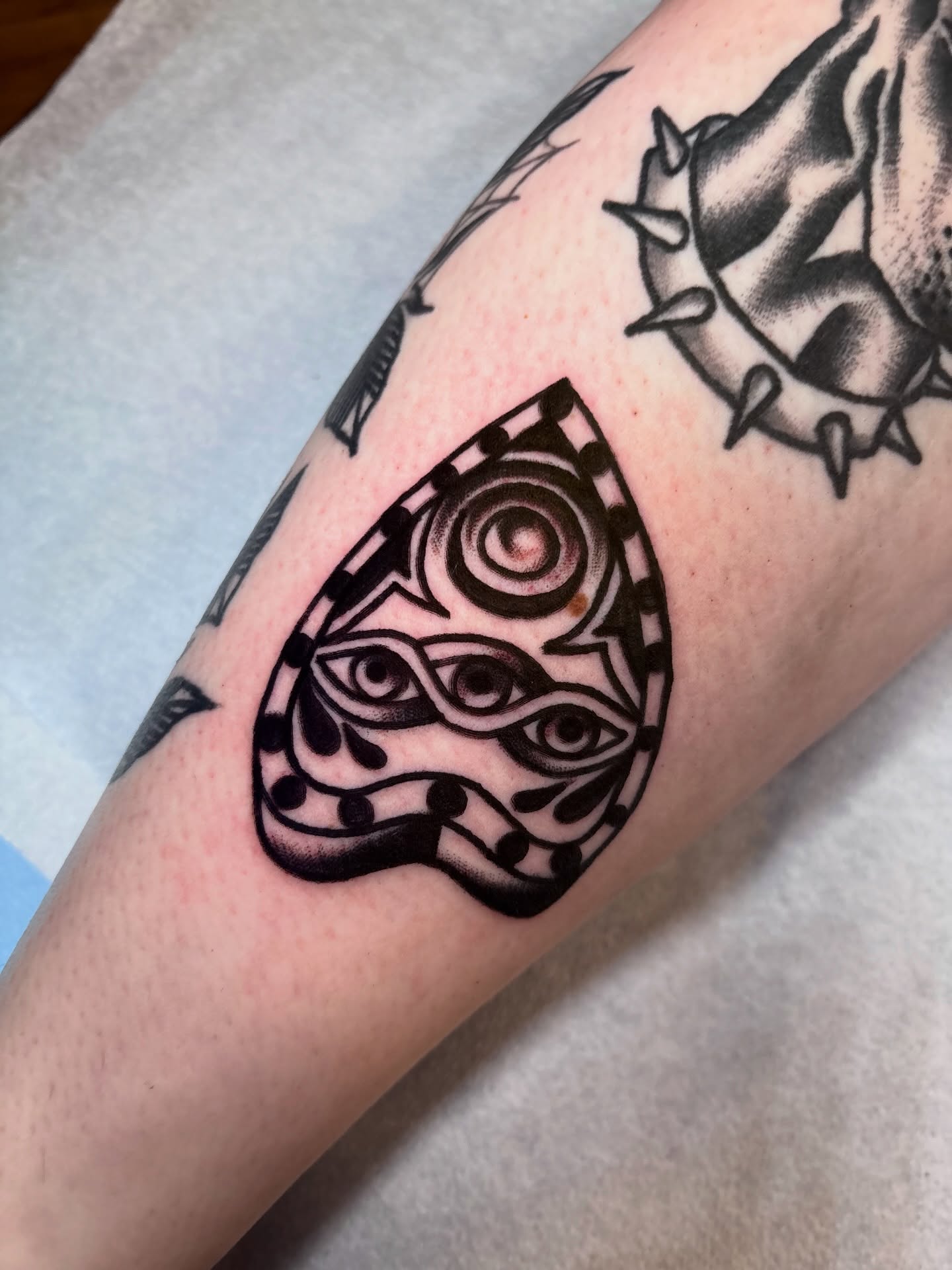 Mask with eyes geometric tattoo on the forearm by Nick