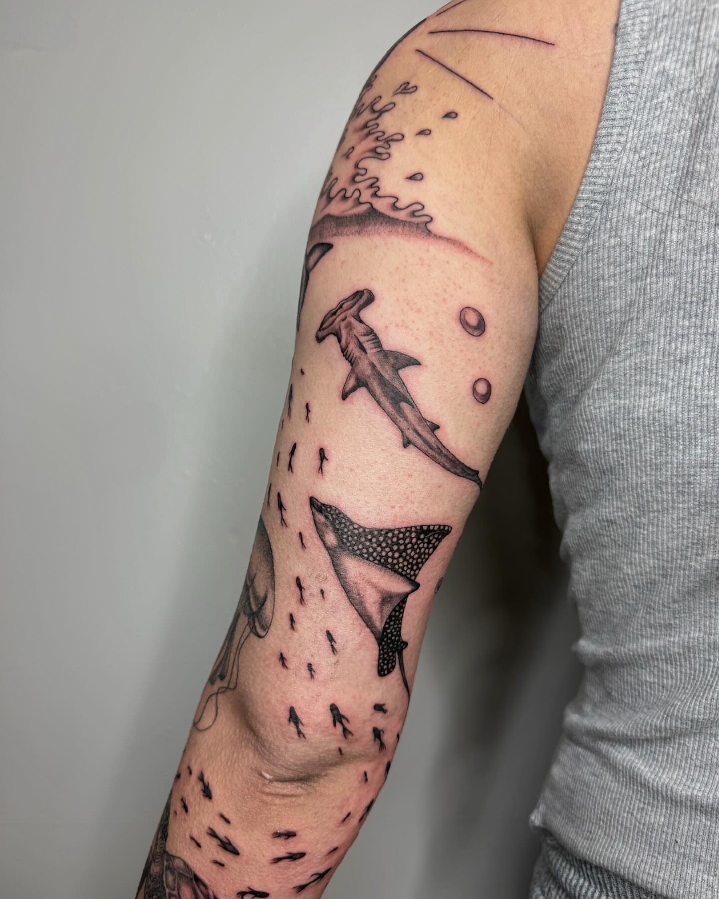 Sharks and fish dotwork tattoo on the forearm by Imani