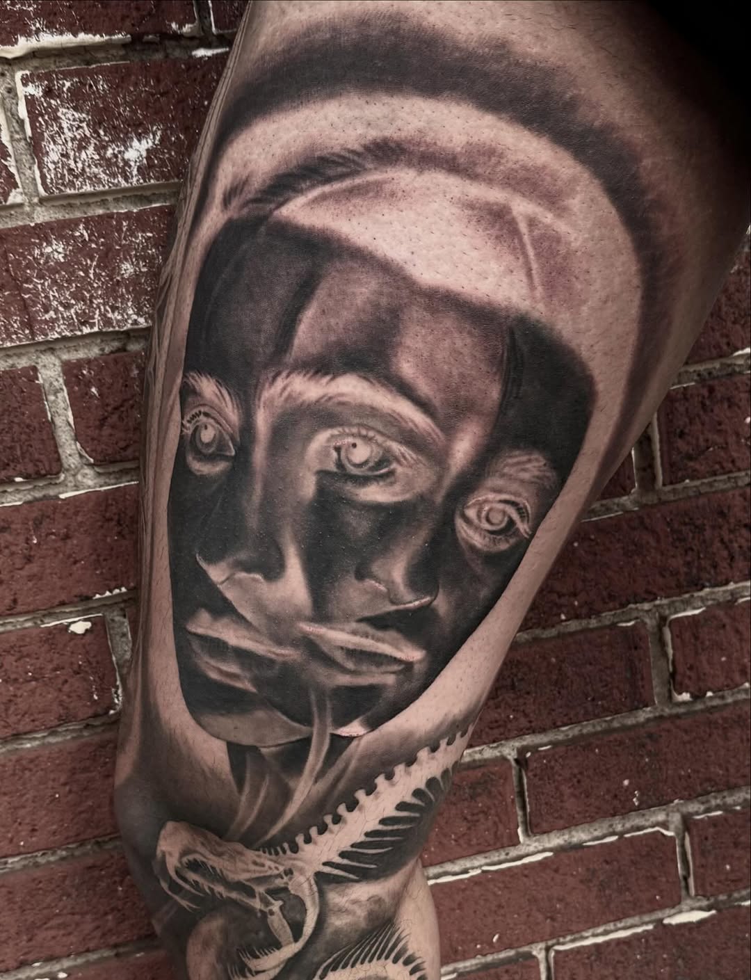 Surreal face and snake skeleton surrealism tattoo on the forearm by Jeremiah Warner