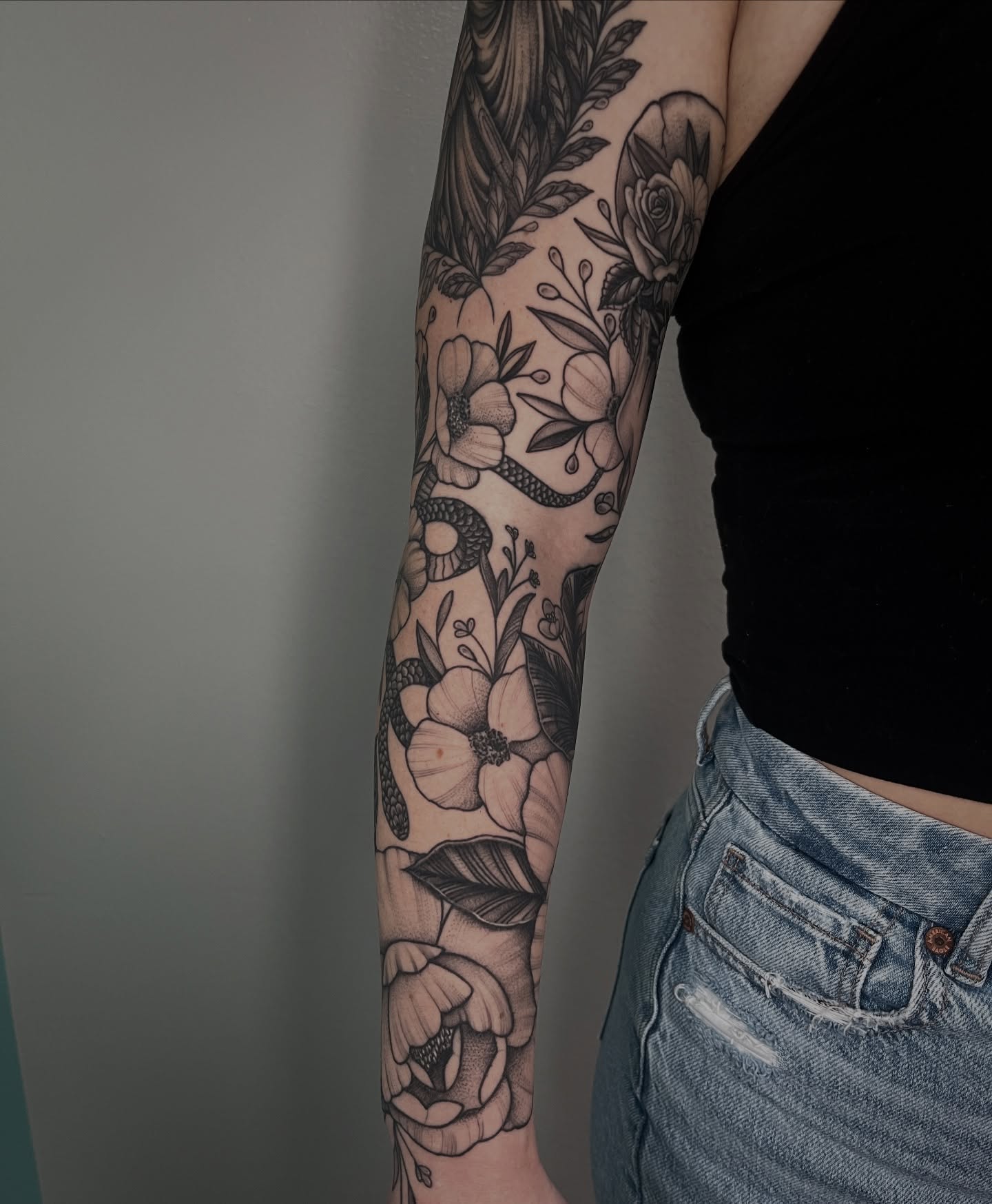 Floral and snake realism tattoo on the forearm by Jordan Hunt