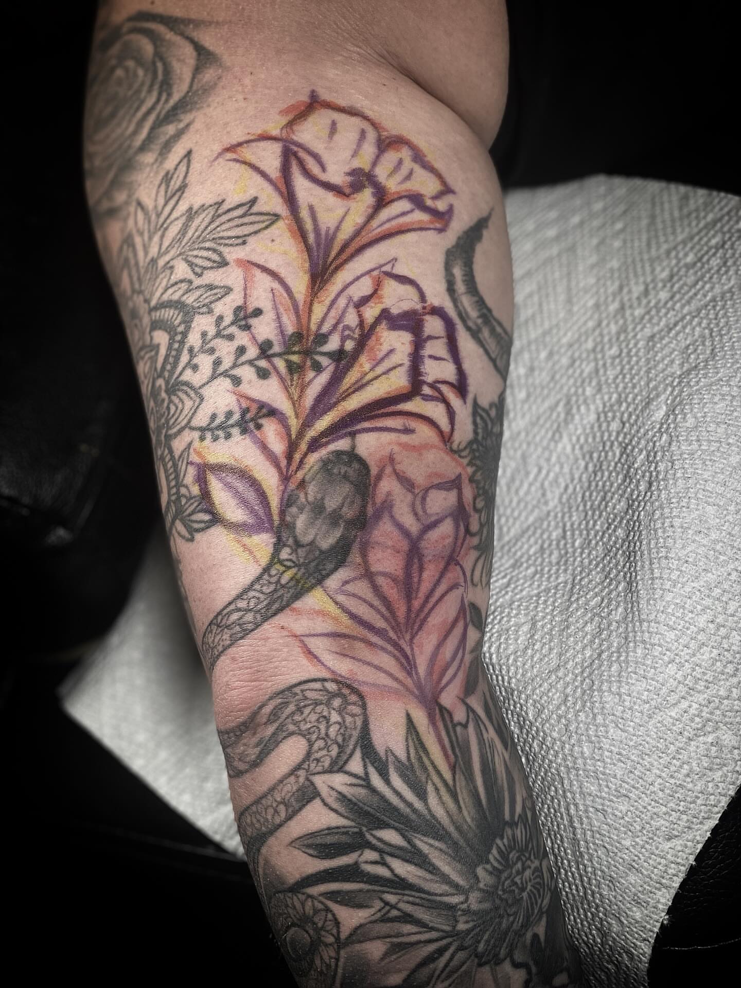 Snake and flowers neo-traditional tattoo on the forearm by Chris Klee