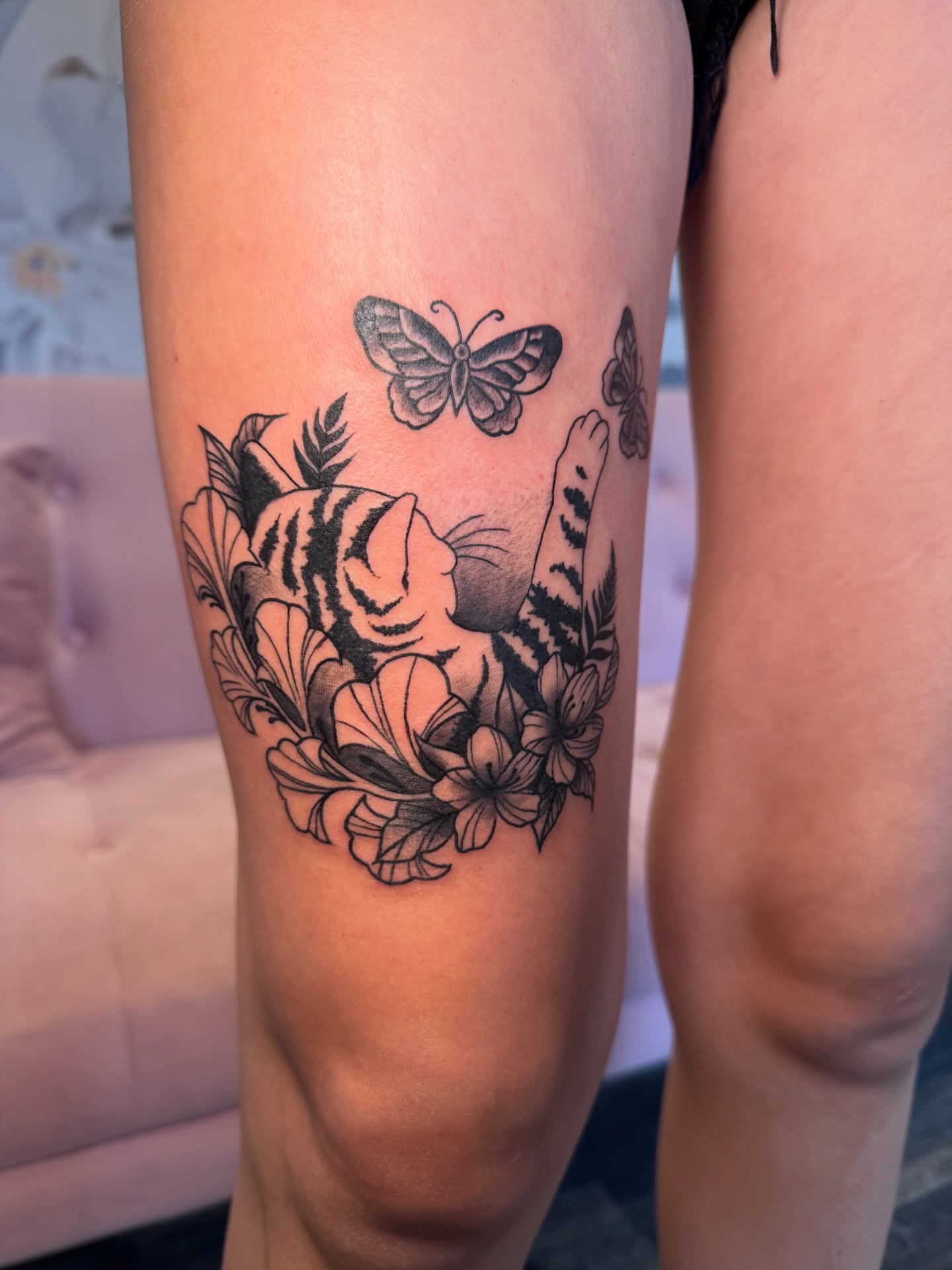 Cat and flowers black and grey tattoo on the thigh by Kinzi Brown