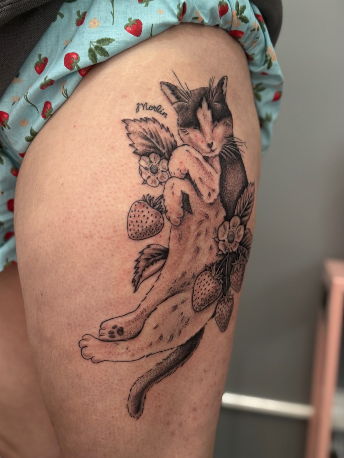 Cat and strawberry realism tattoo on the thigh by Kamakana Pankiwska