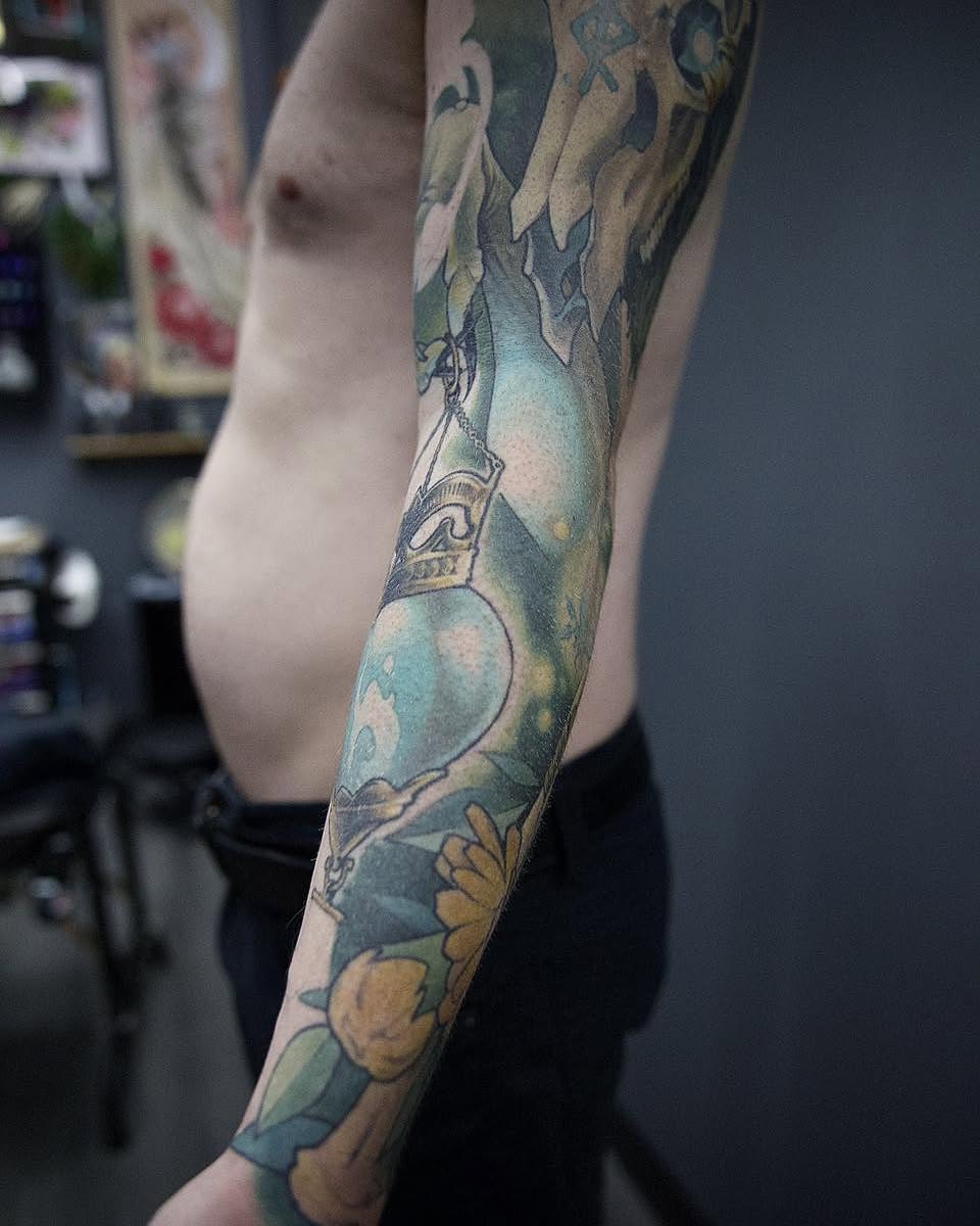 Glass bottle with flowers tattoo on the forearm by Harper Clark