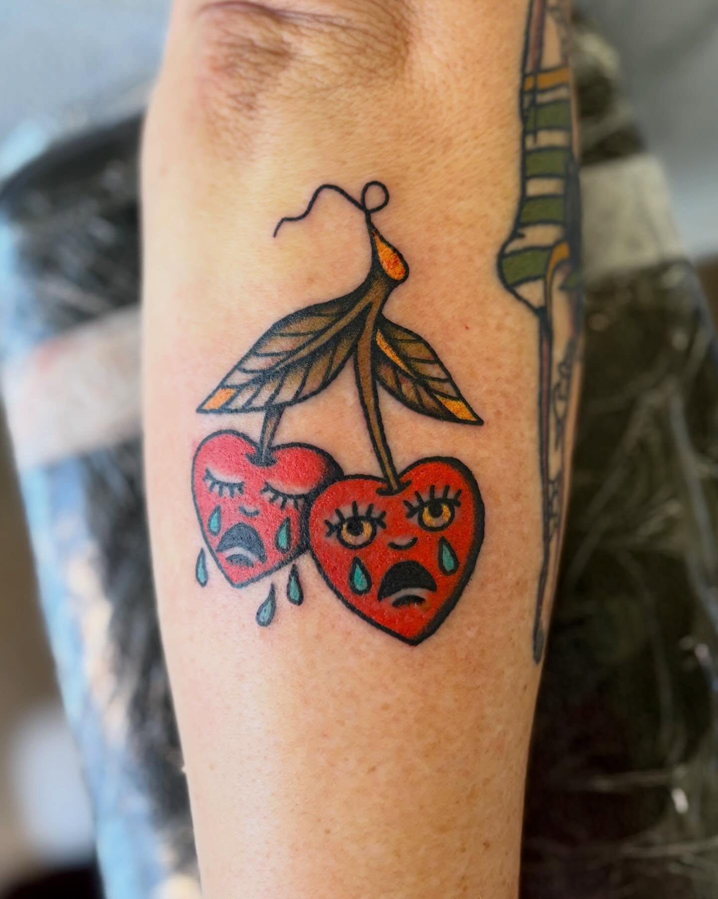 Crying cherries American traditional tattoo on the forearm by Tia Cave