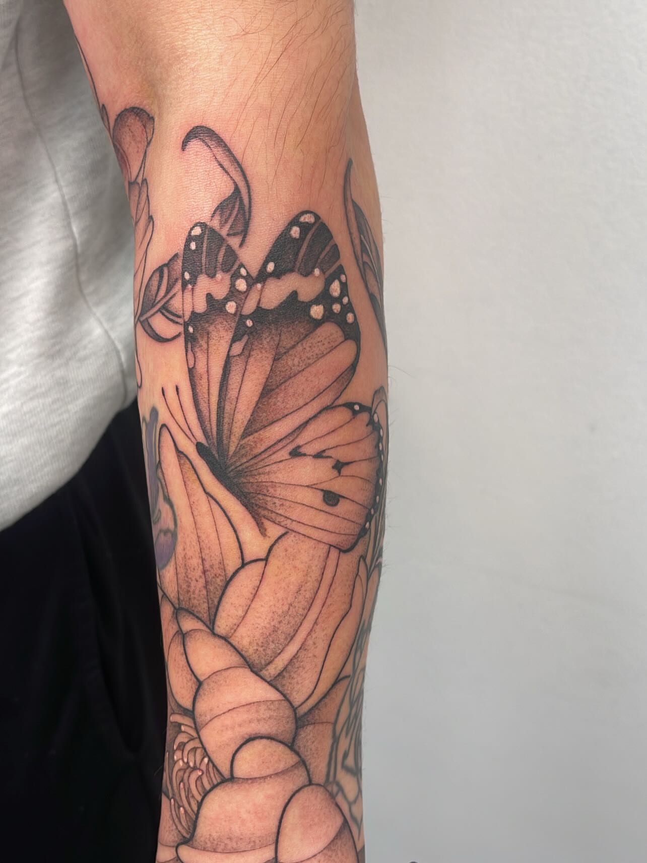 Butterfly and flower dotwork tattoo on the forearm by Miesha Busker