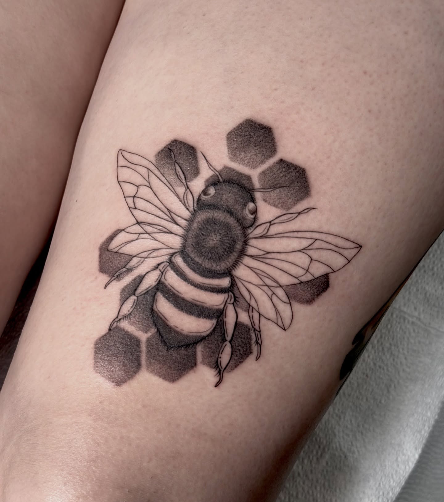 Bee black and grey tattoo on the thigh by Barbara Gonzalez