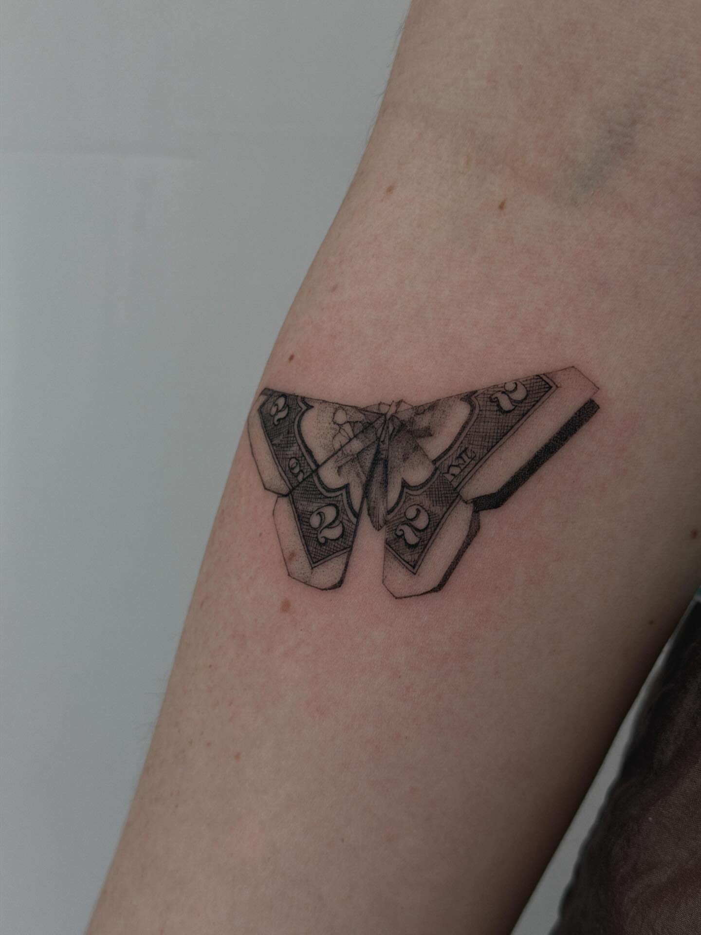 Dollar bill butterfly black and grey tattoo on the forearm by Hannah Matthews