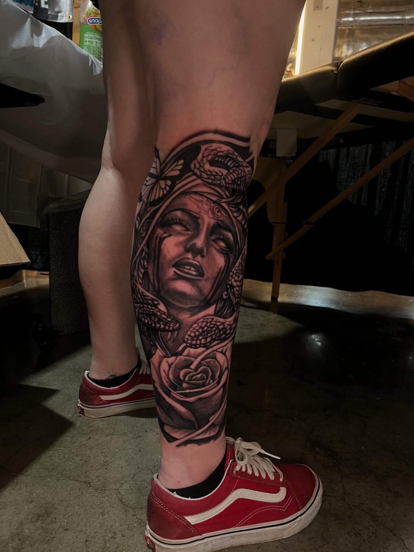 Woman with snake and rose realism tattoo on the calf by Dee