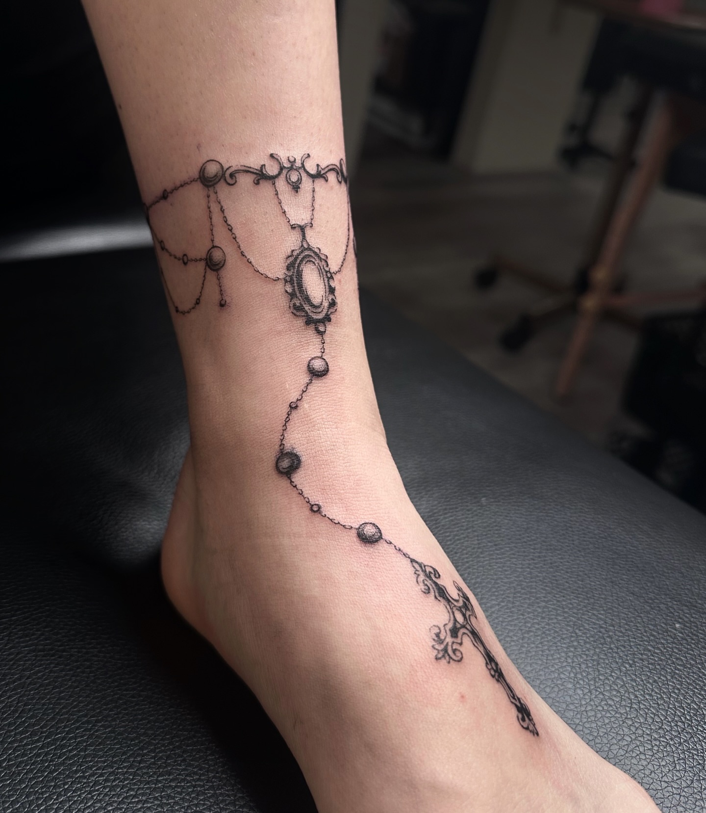 Necklace black and grey tattoo on the foot by Micky, Austin, Texas
