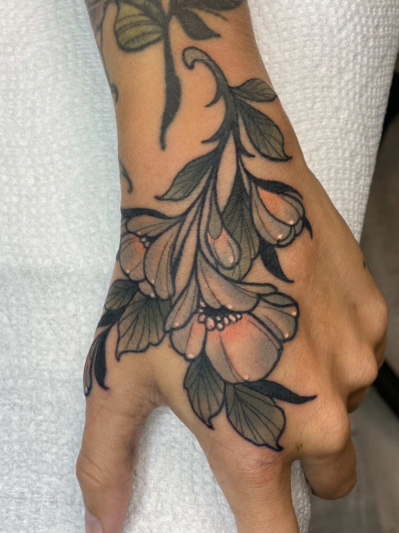 Floral arrangement black and grey tattoo on the hand by Kyle Behr