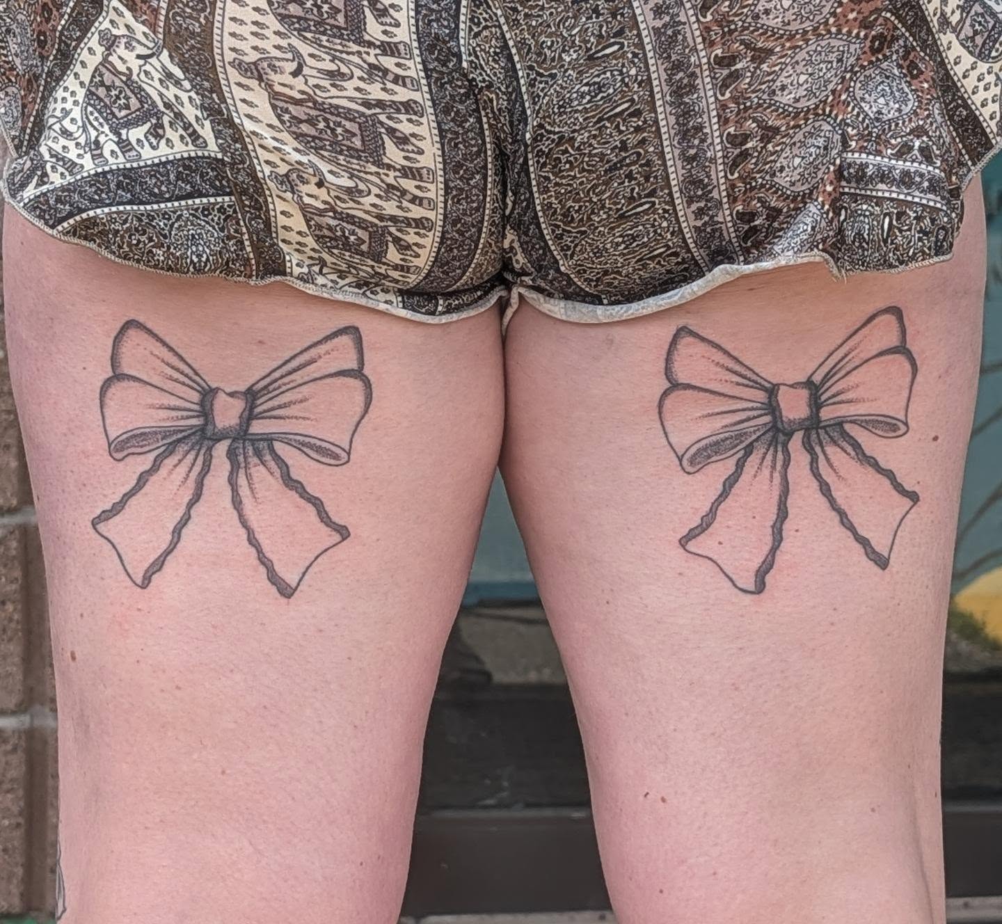 Bow black and grey tattoo on the thigh by Carissa Berardi