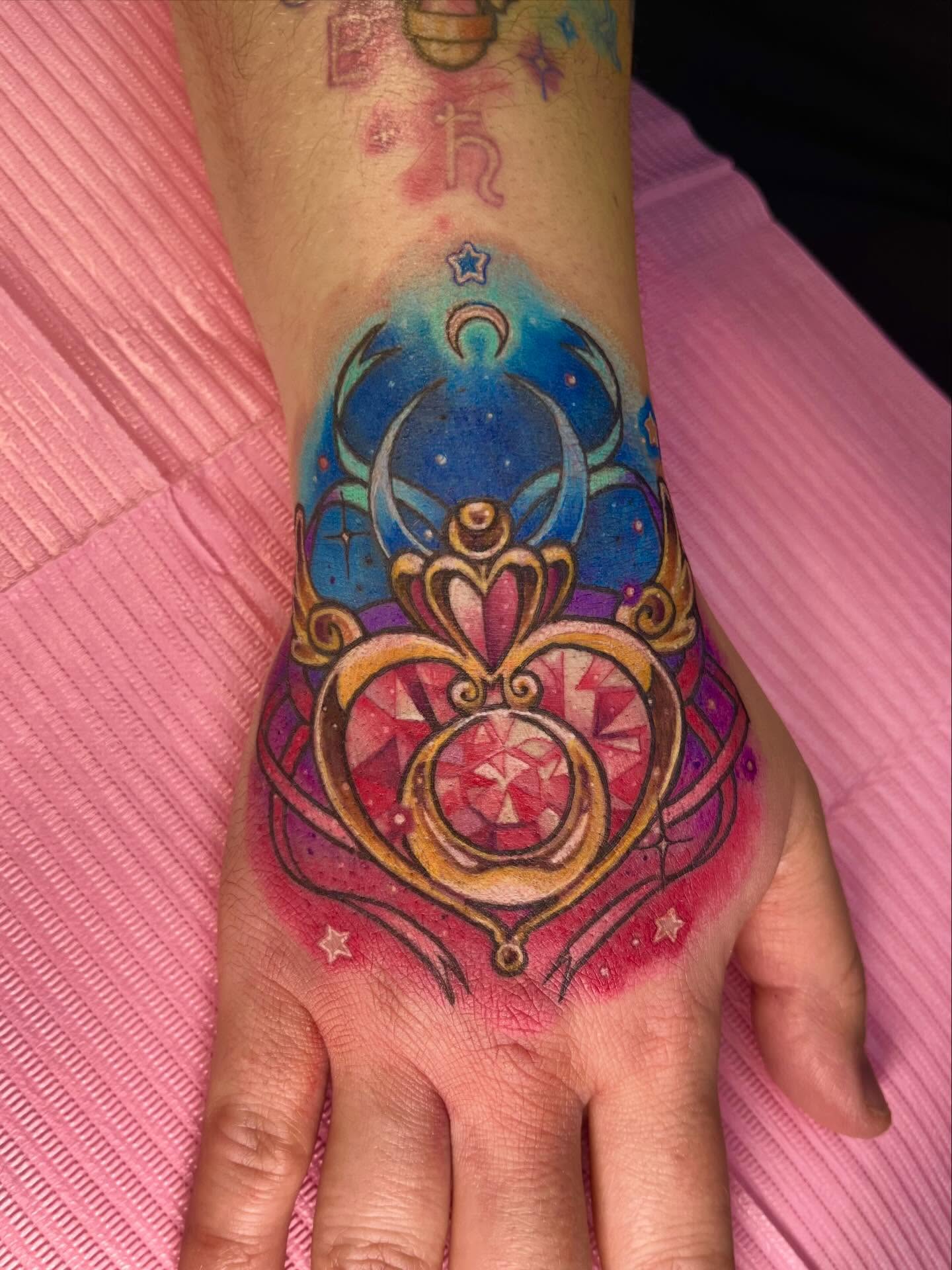 Heart-shaped pendant new school tattoo on the hand by Cami Rose