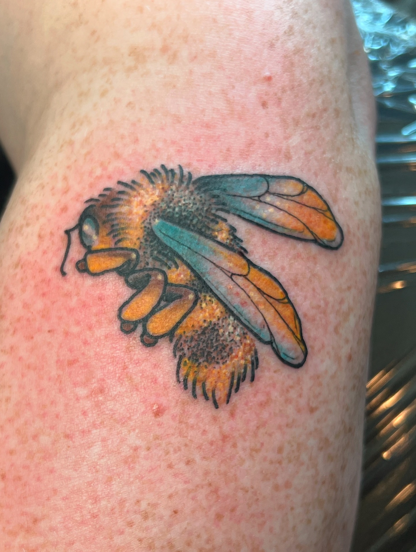 Bee new school tattoo on the upper arm by Andrea Patterson