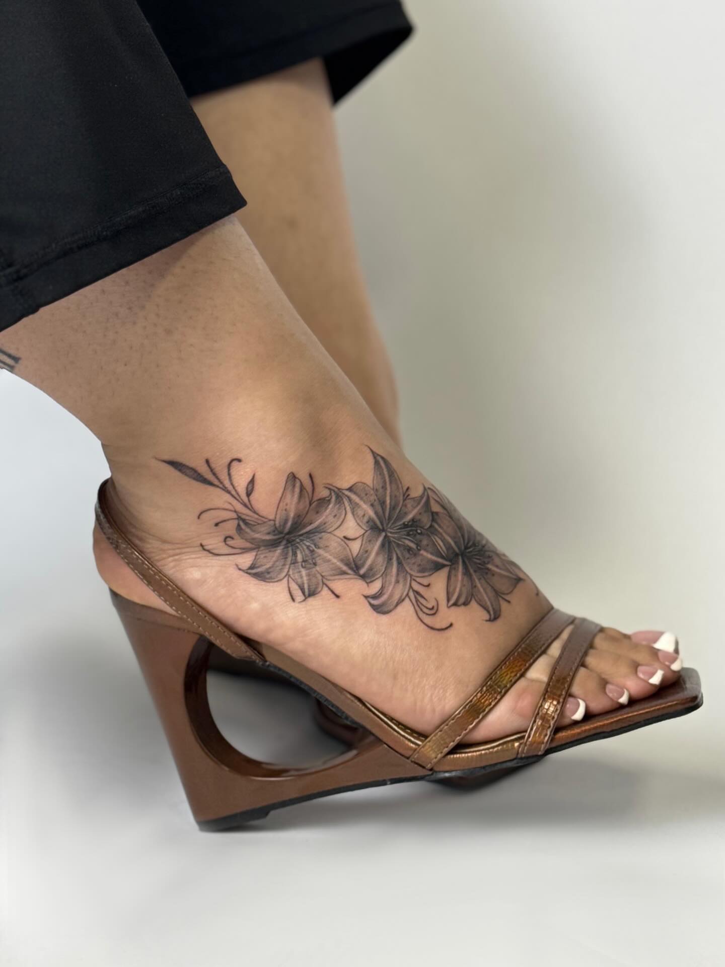 Lilies black and grey tattoo on the foot by Nevaeh tattoo artist